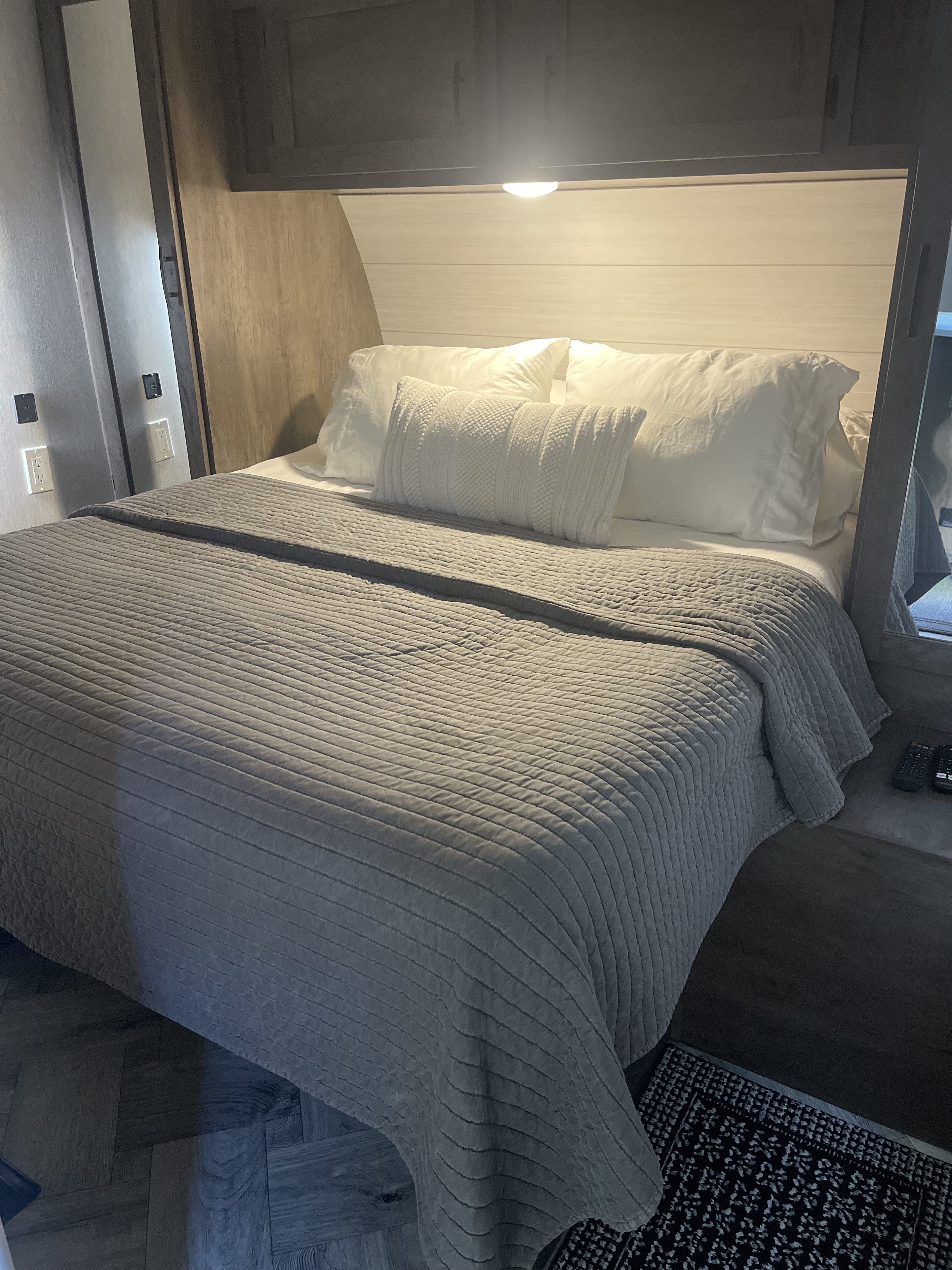 Cozy RV rental bedroom features a comfy grey bed, white pillows, built-in storage, and reading light. Ideal for travel.. Forest River Evo T2990 2022