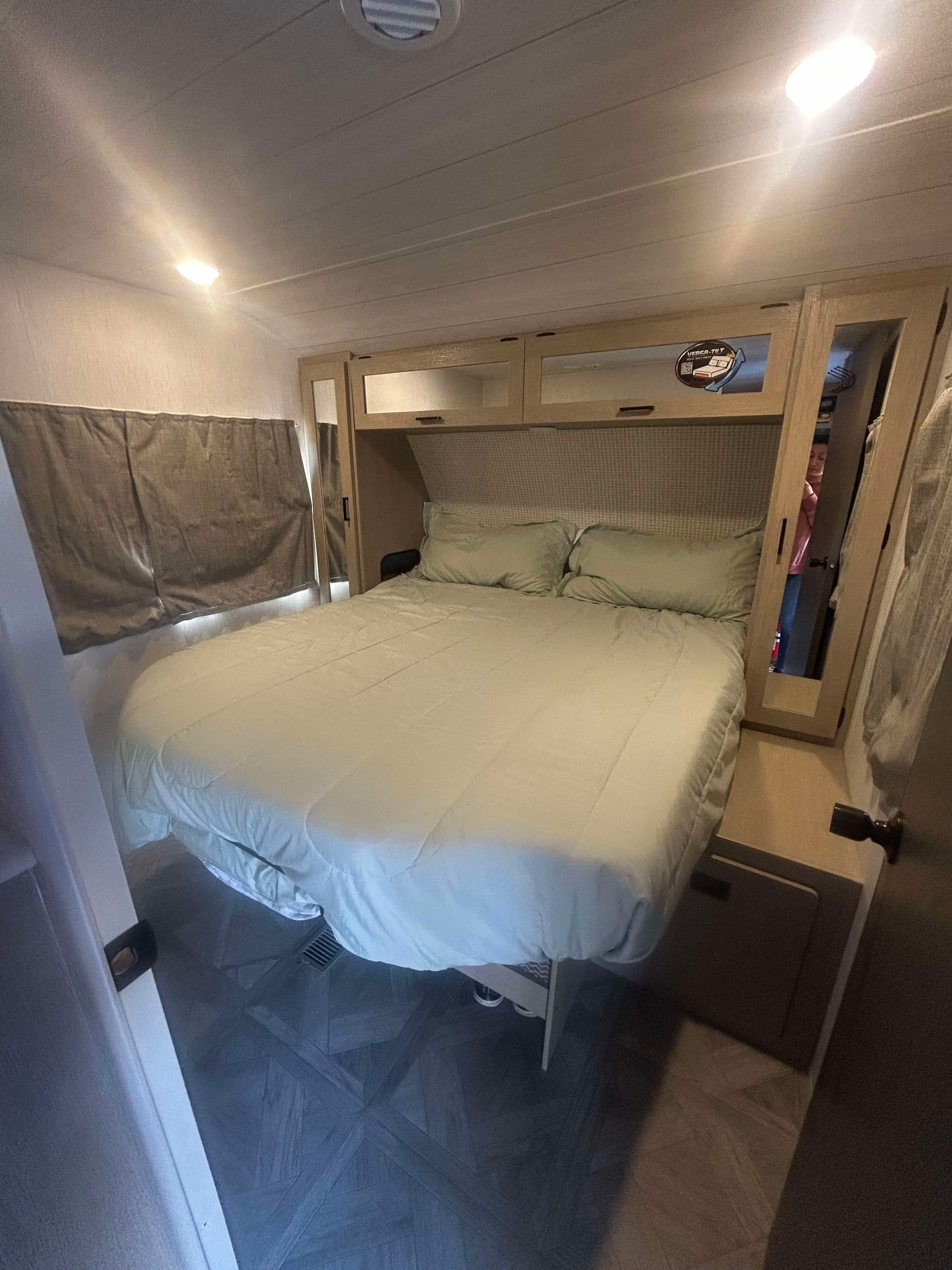 Bright RV rental interior: A cozy bedroom with a large bed, overhead storage, mirrored closets, and a window.. Forest River Salem Platinum 2024