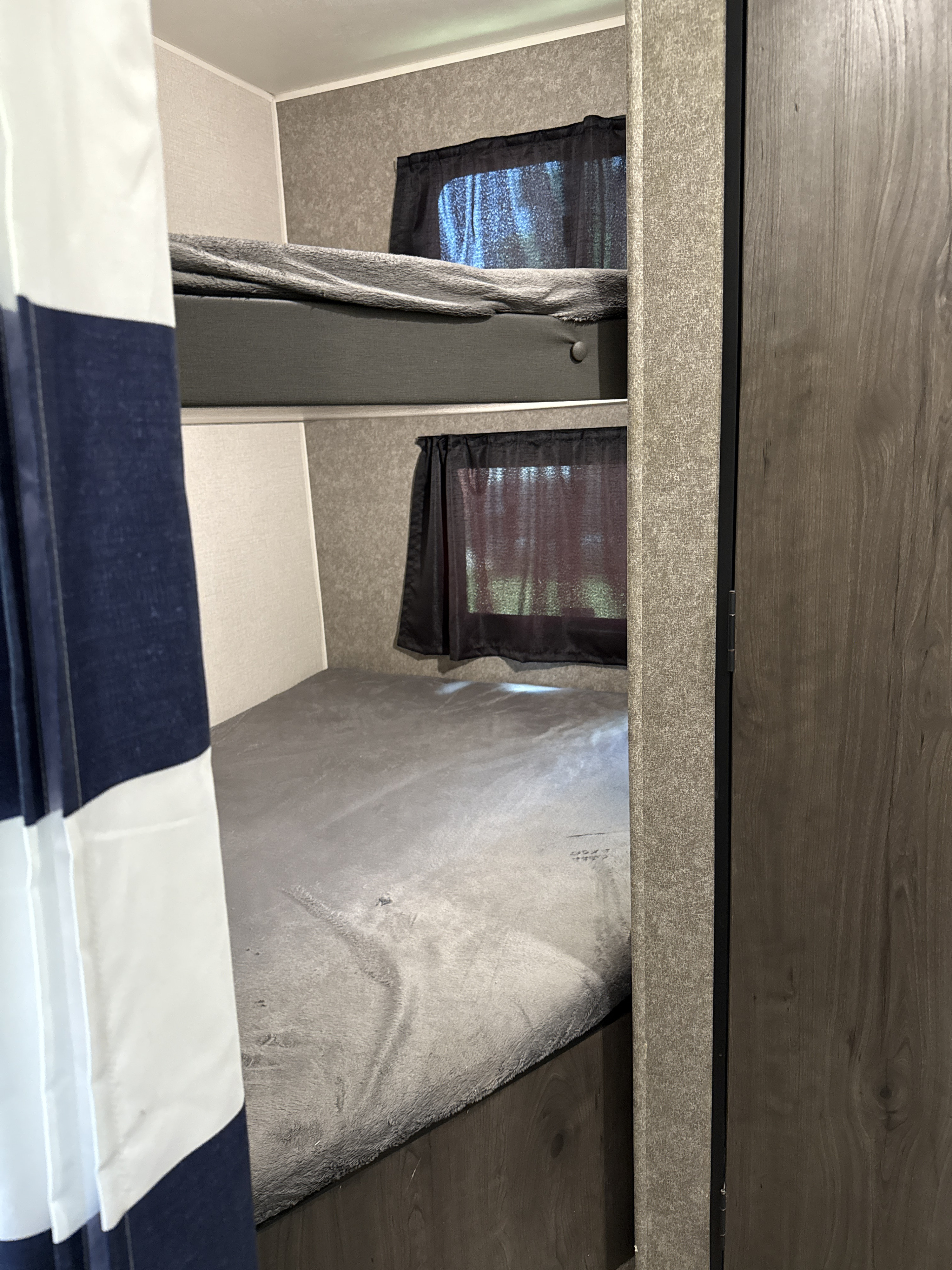 RV rental interior: two stacked bunk beds with grey bedding, windows, and black privacy curtains.. Highland Ridge RV Open Range 2021