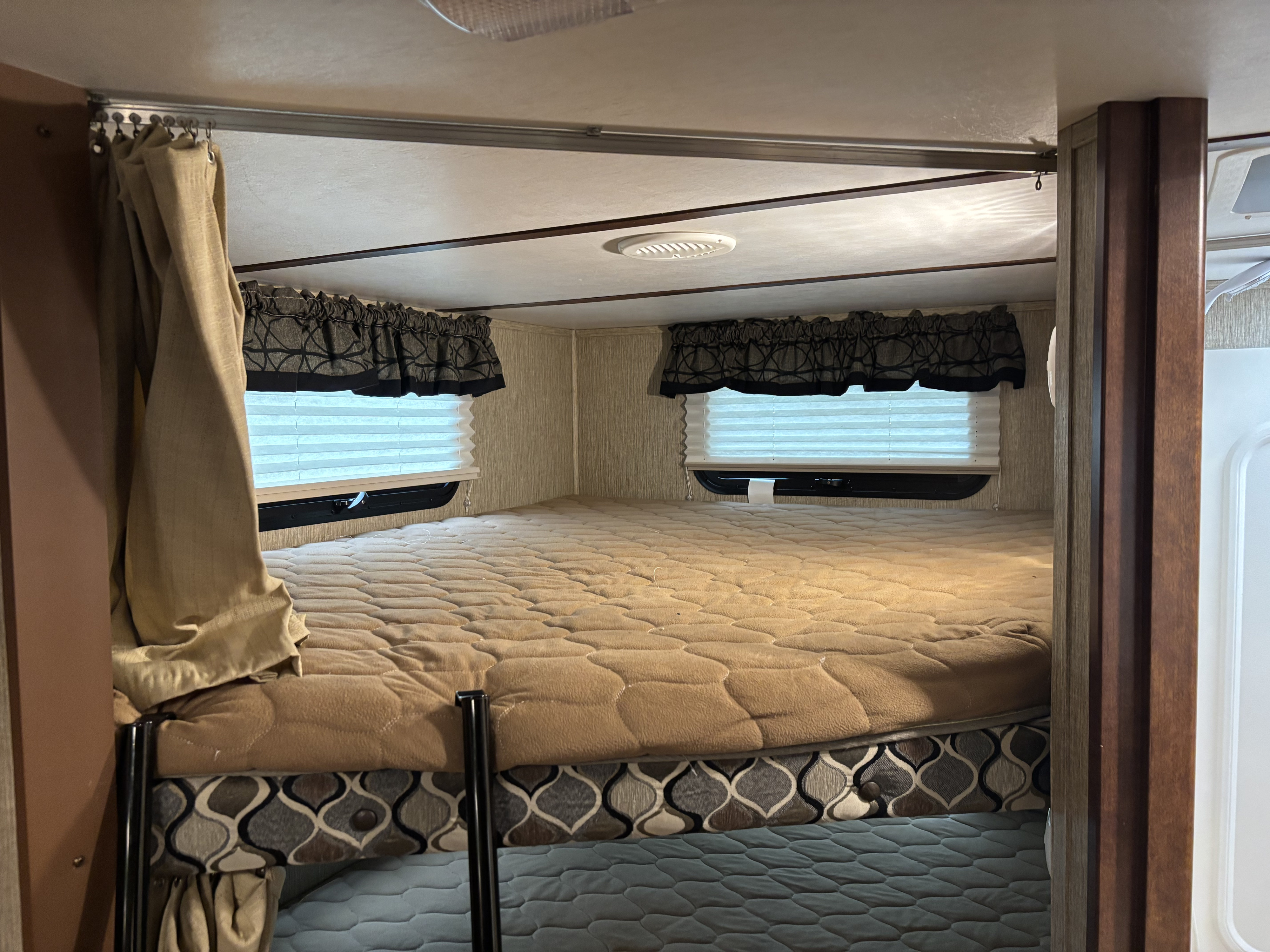 Inside an RV rental: a comfortable bunk sleeping area with windows, blinds, and privacy curtains.. Keystone RV Outback Ultra-Lite 2017