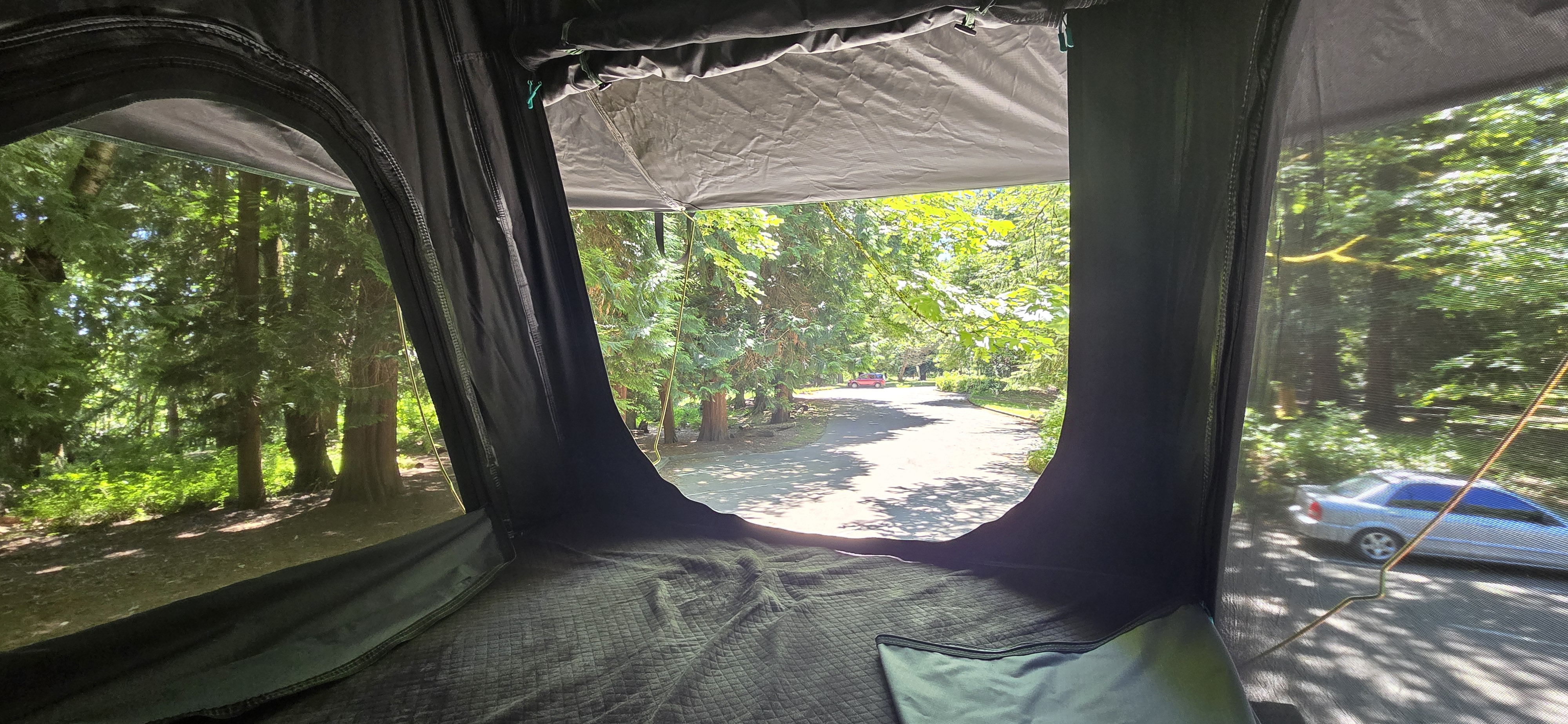 Cozy **rv rental** rooftop tent view: lush trees, a winding road, and parked cars outside. Ideal for nature escapes.. Mercedes Sprinter 2023