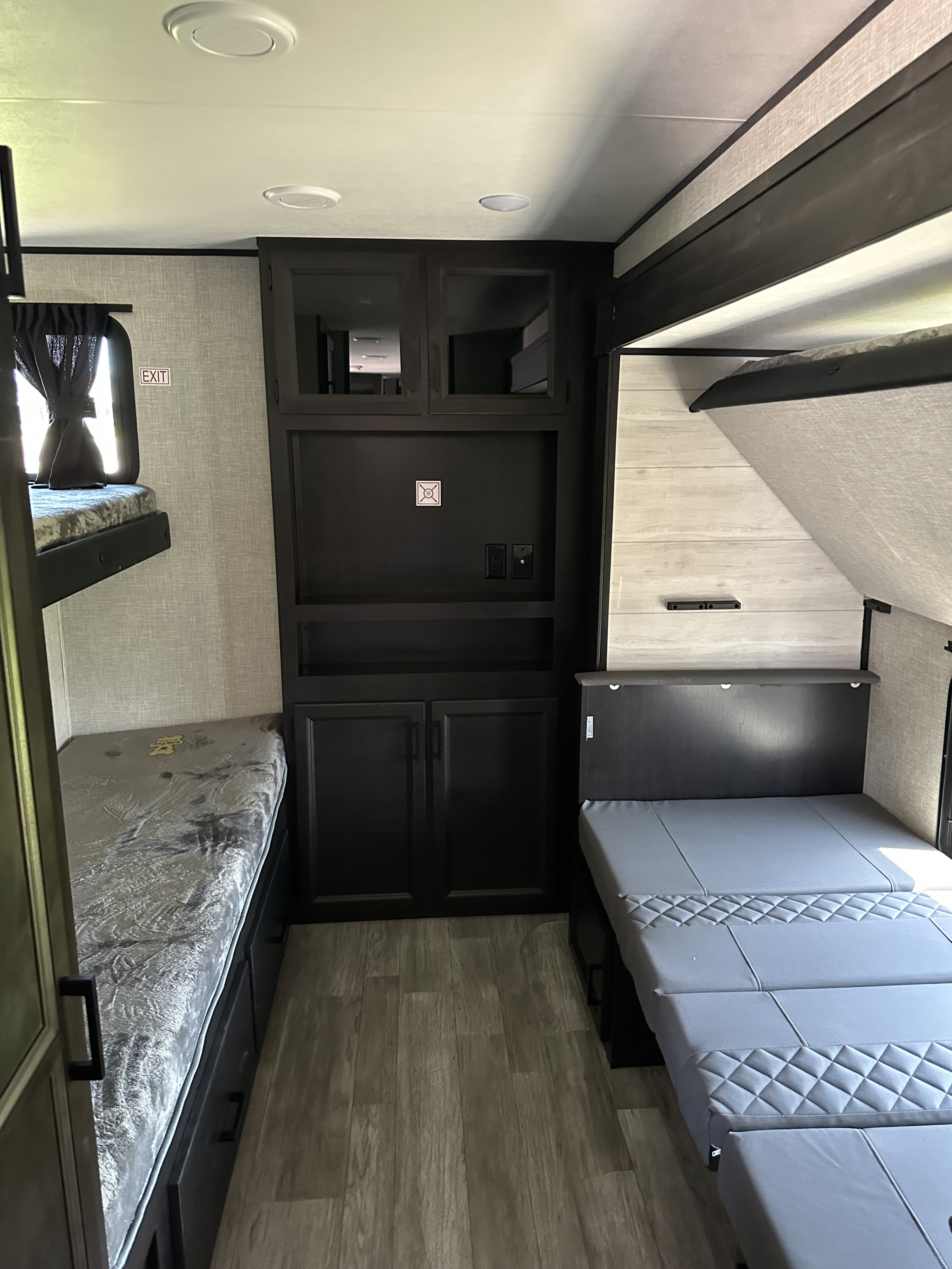 Modern RV rental interior featuring bunk beds, a central entertainment/storage unit, and a convertible sleeping area.. Jayco Jay Flight 2023