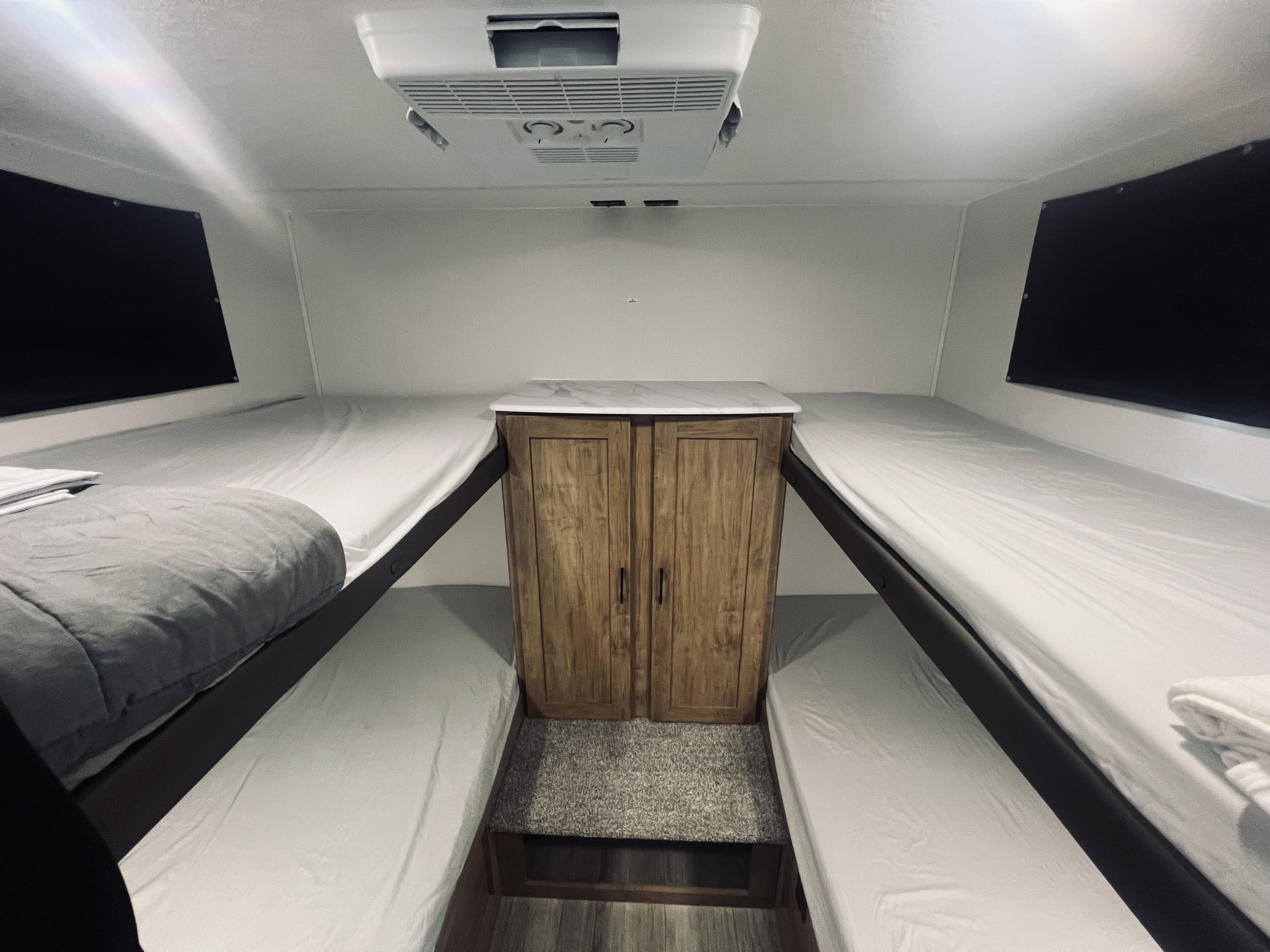 Spacious RV rental bunk room with four neat bunk beds, a central cabinet, and overhead AC, ready for your adventure.. Forest River Coachmen Freedom Express Select 2024