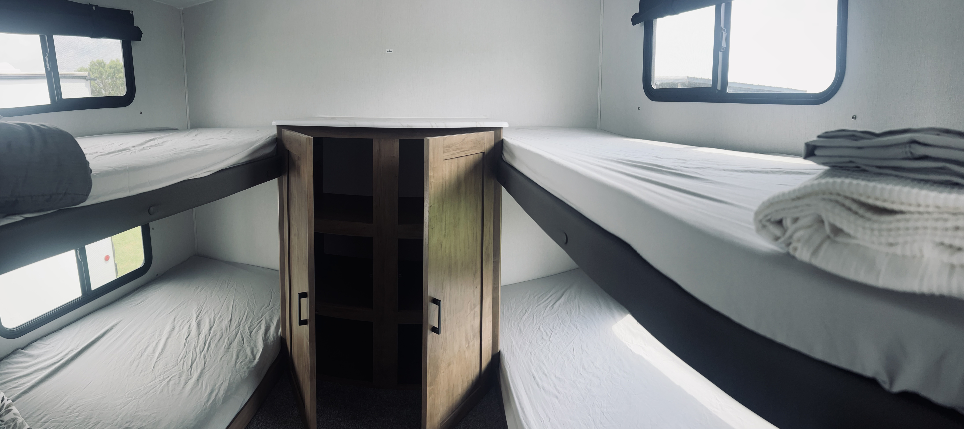 Spacious RV rental interior featuring four bunk beds, two on each side, and a central storage cabinet.. Forest River Coachmen Freedom Express Select 2024