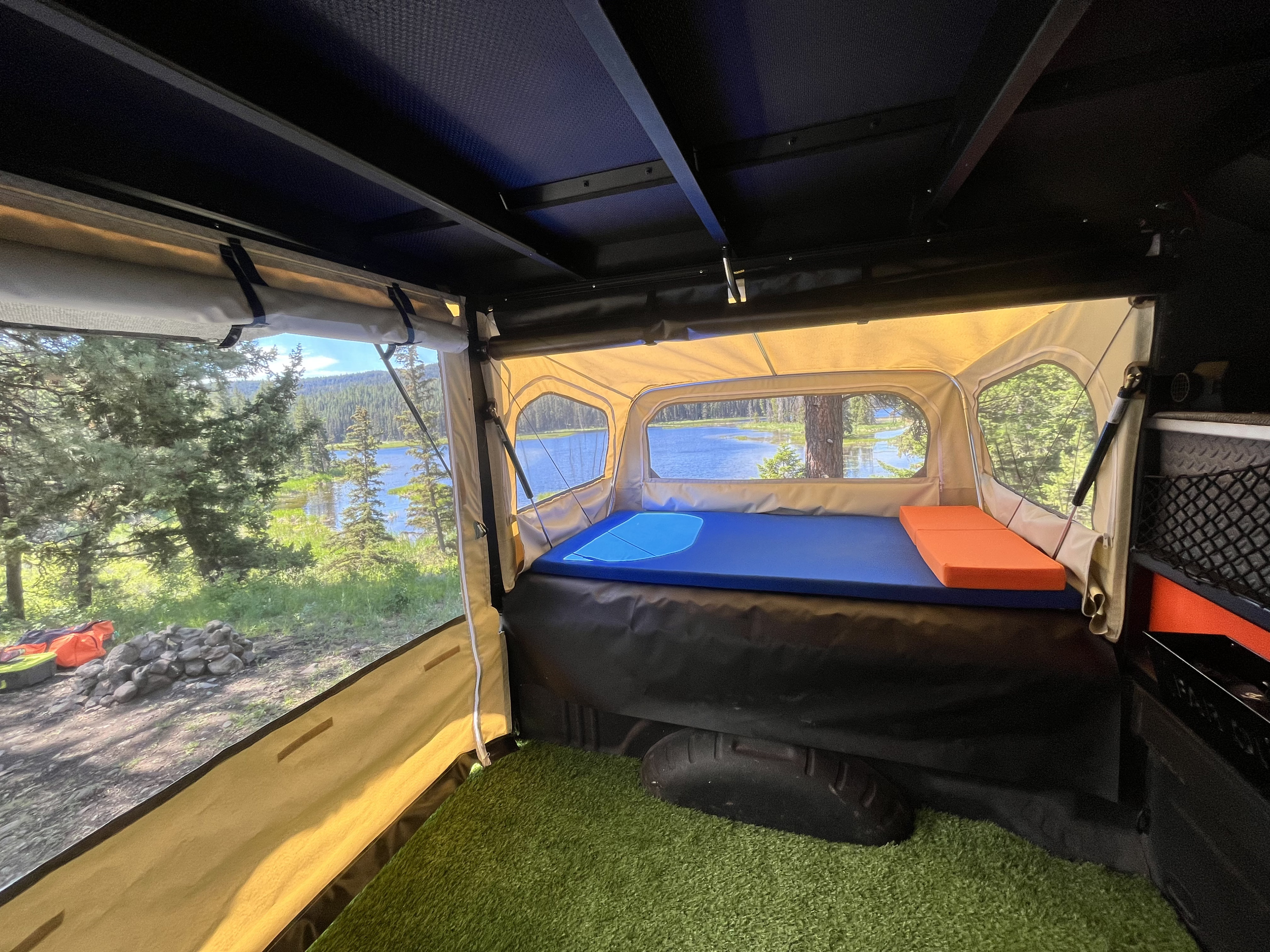 Cozy RV rental interior with a bed, offering scenic lake views through large windows. Perfect for outdoor camping.. Far-Out Camper Far-Out Camper 6.5 ft 2024
