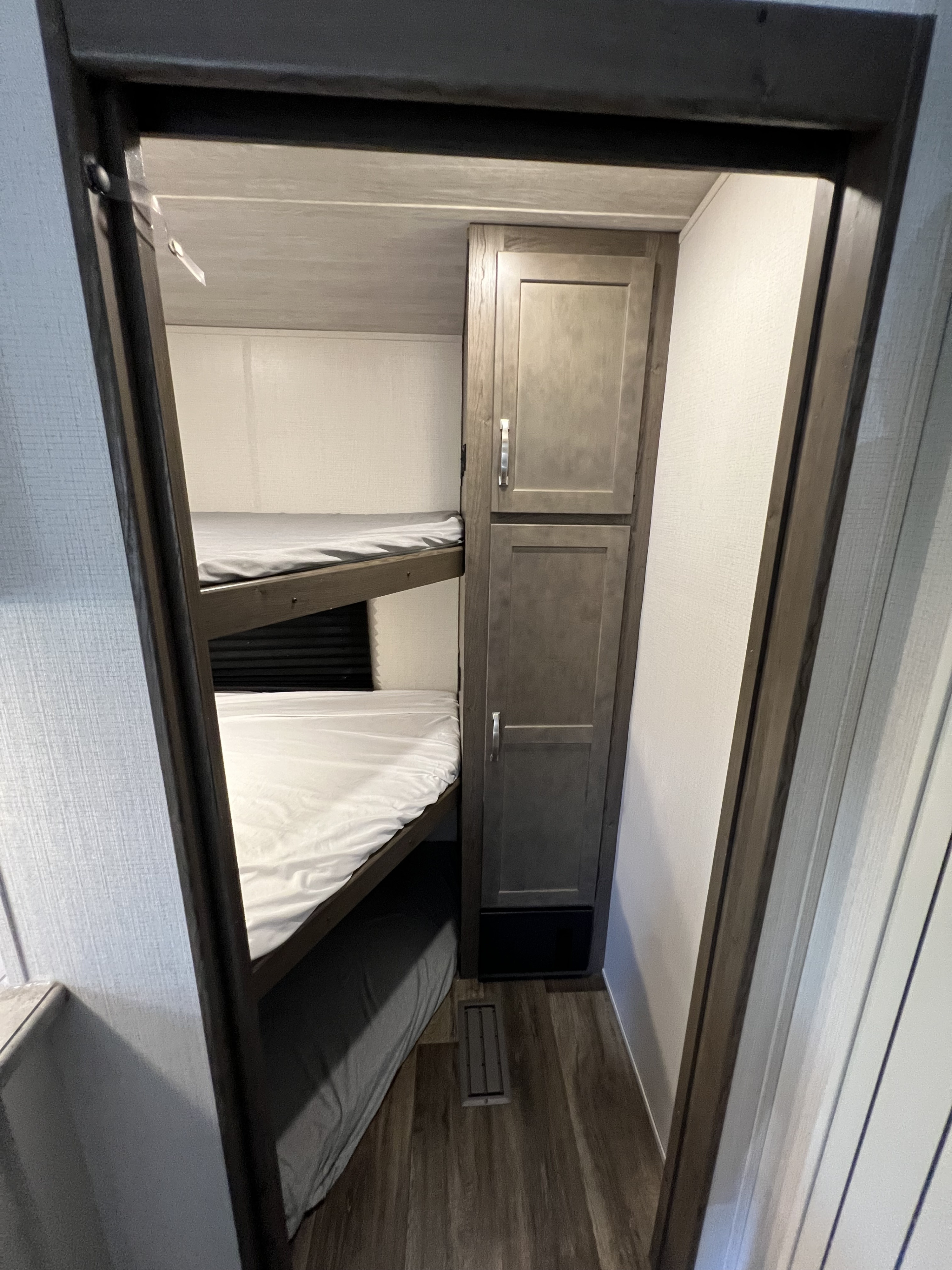 RV rental bunk bed sleeping area with a practical storage cabinet. Features two beds with mattresses.. Keystone RV Cougar 2023