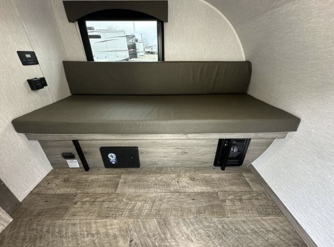 Comfortable RV rental interior: bench seating/bed, window view, and compact living space for your adventure.. Sunset Park RV SunRay 2024