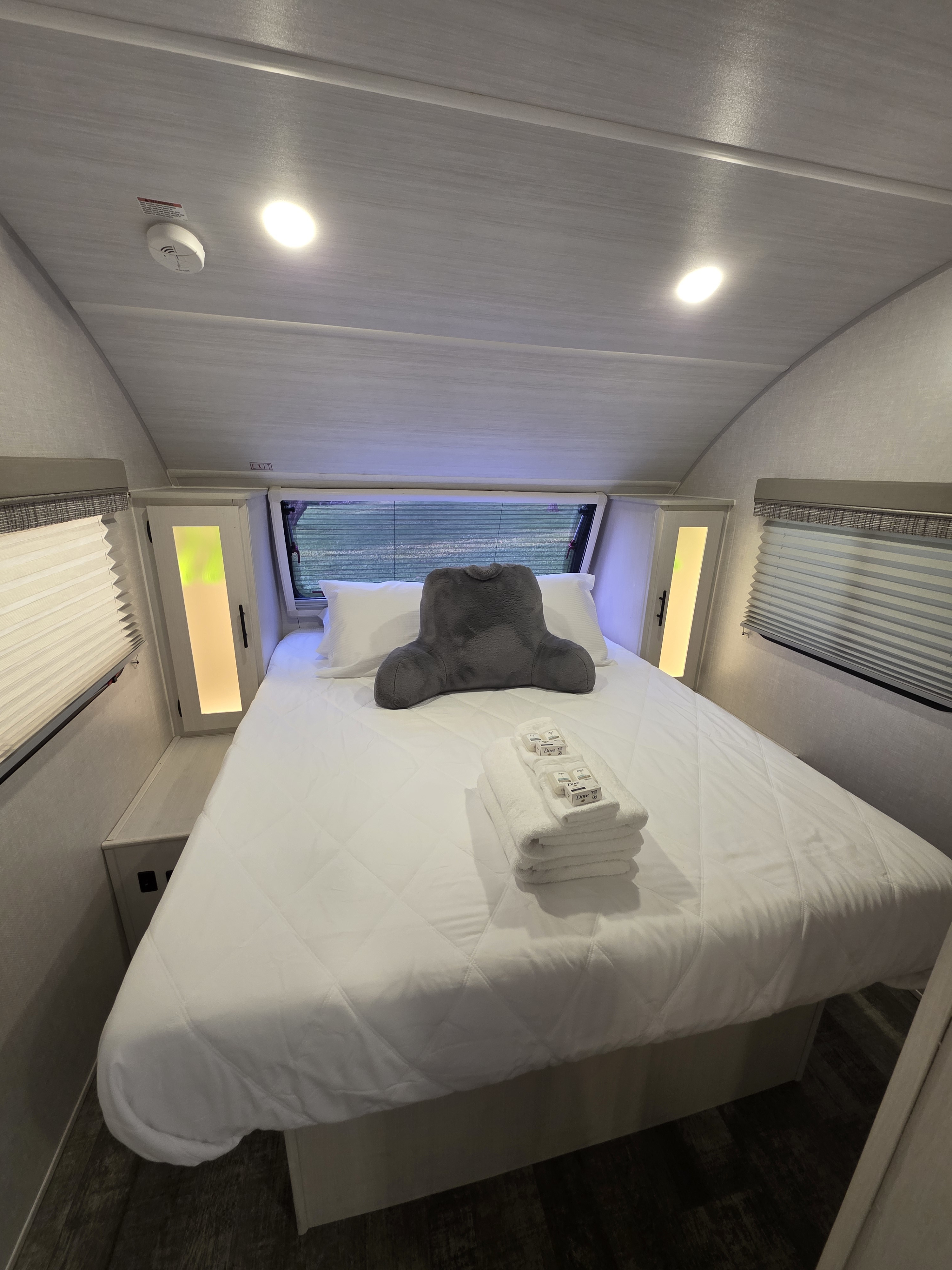 An RV rental interior: A modern, cozy bedroom with a neatly made bed, fresh towels, and ambient lighting.. R-Pod 202 2022