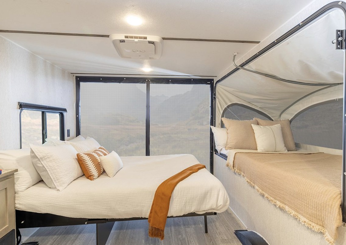 Comfortable RV rental interior with a spacious main bed and a cozy pop-out bunk bed, offering scenic views for travel.. Go Lite Boulderback 2025