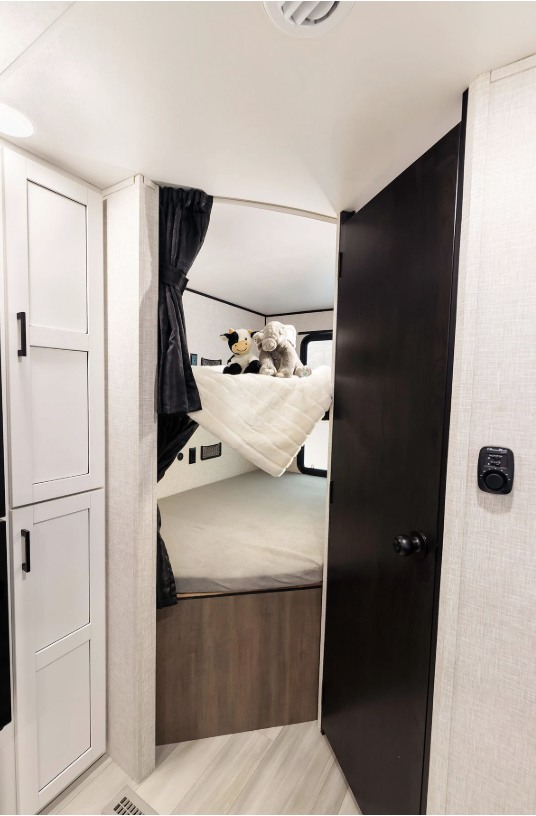 This compact RV rental features a cozy bunk bed area with stuffed animals, perfect for family travel.. Go Play 26BH 2025