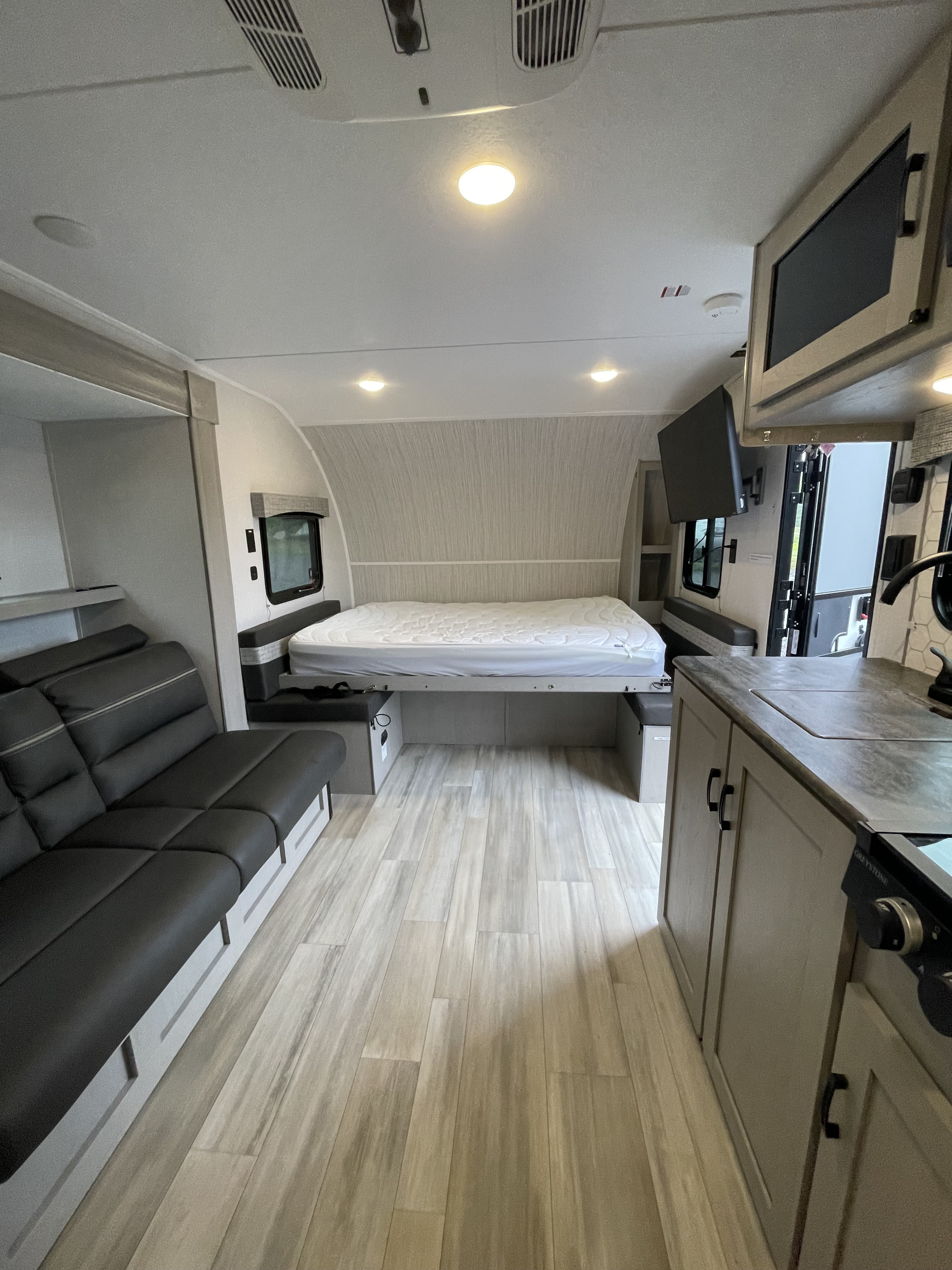 Tour this rv rental: a cozy and functional interior with a large bed, plush sofa, compact kitchen counter, and light wood flooring.. Forest River Coachmen Clipper 2024