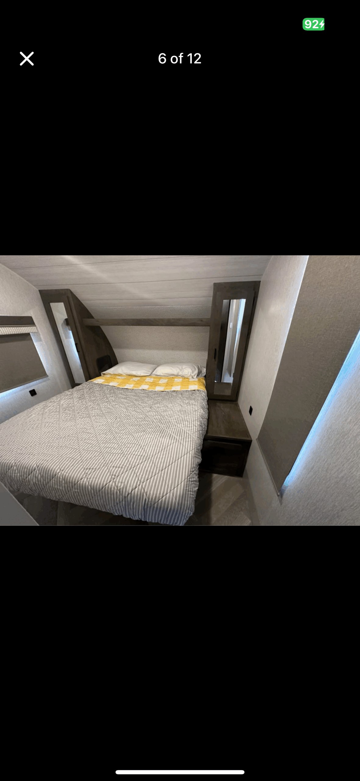 Cozy RV rental bedroom with a striped bedspread, pillows, built-in storage, and window. A comfortable sleep space.. Forest River Wildwood 2024