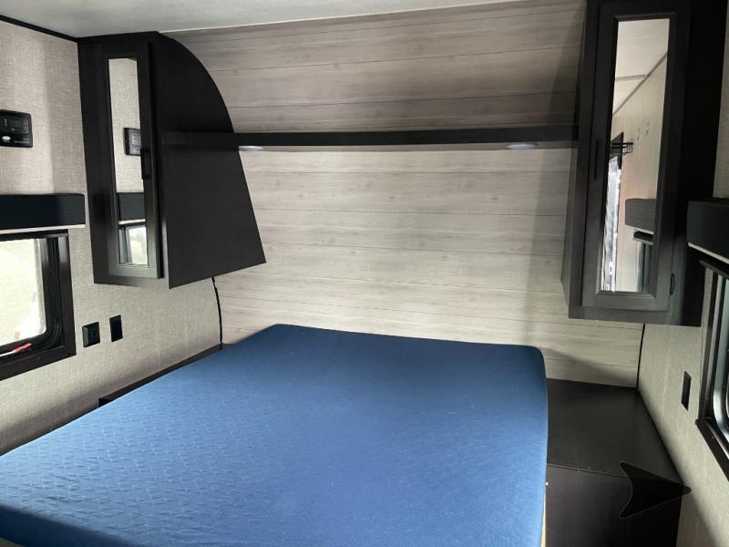 Cozy RV rental bedroom with blue mattress, overhead cabinets, and windows. Ready for your adventure!. Jayco Jay Flight SLX 2022