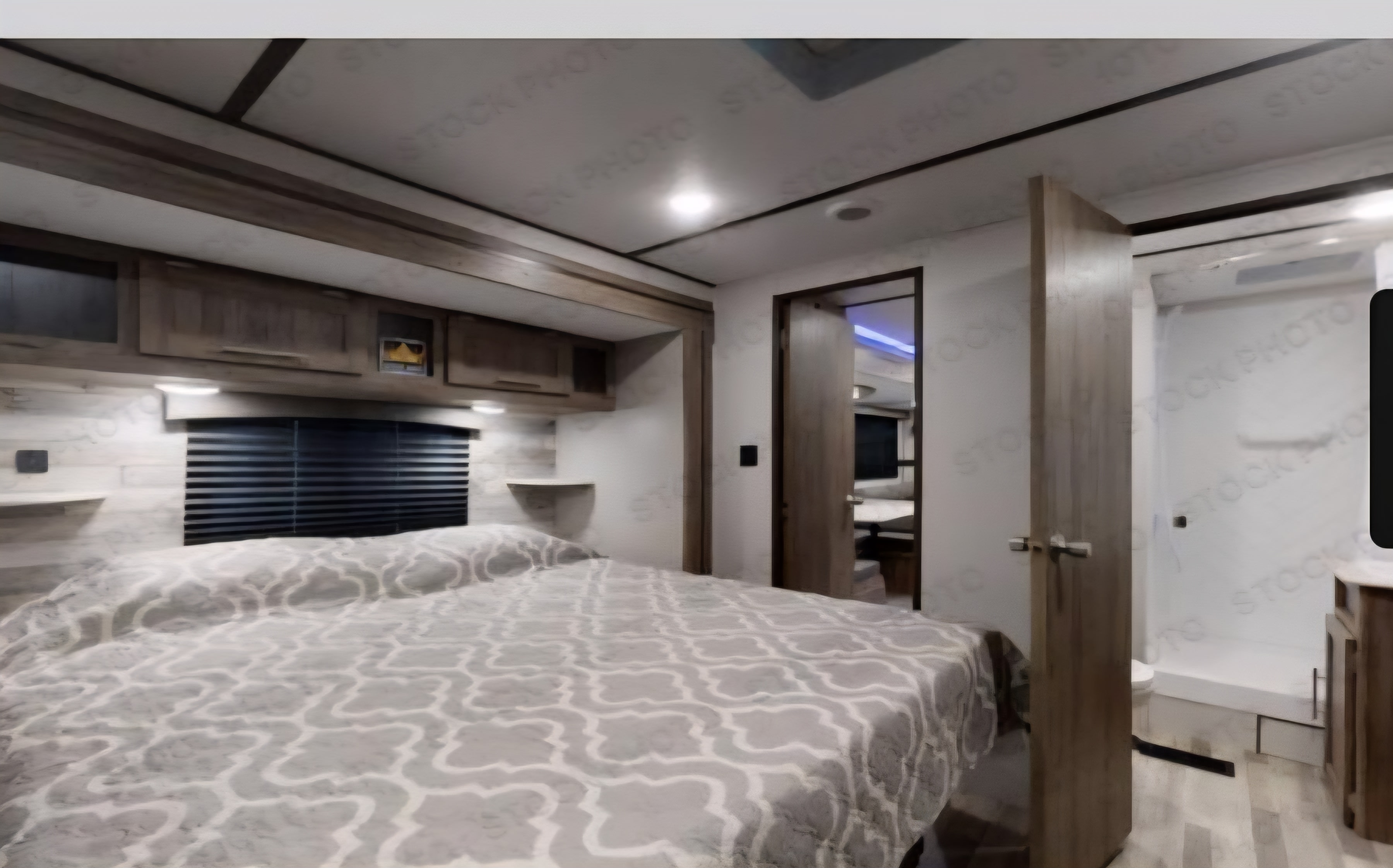 Spacious RV rental bedroom with a large bed, modern wood finishes, and an en-suite bathroom, perfect for comfortable travel.. Crossroads RV Zinger 2021