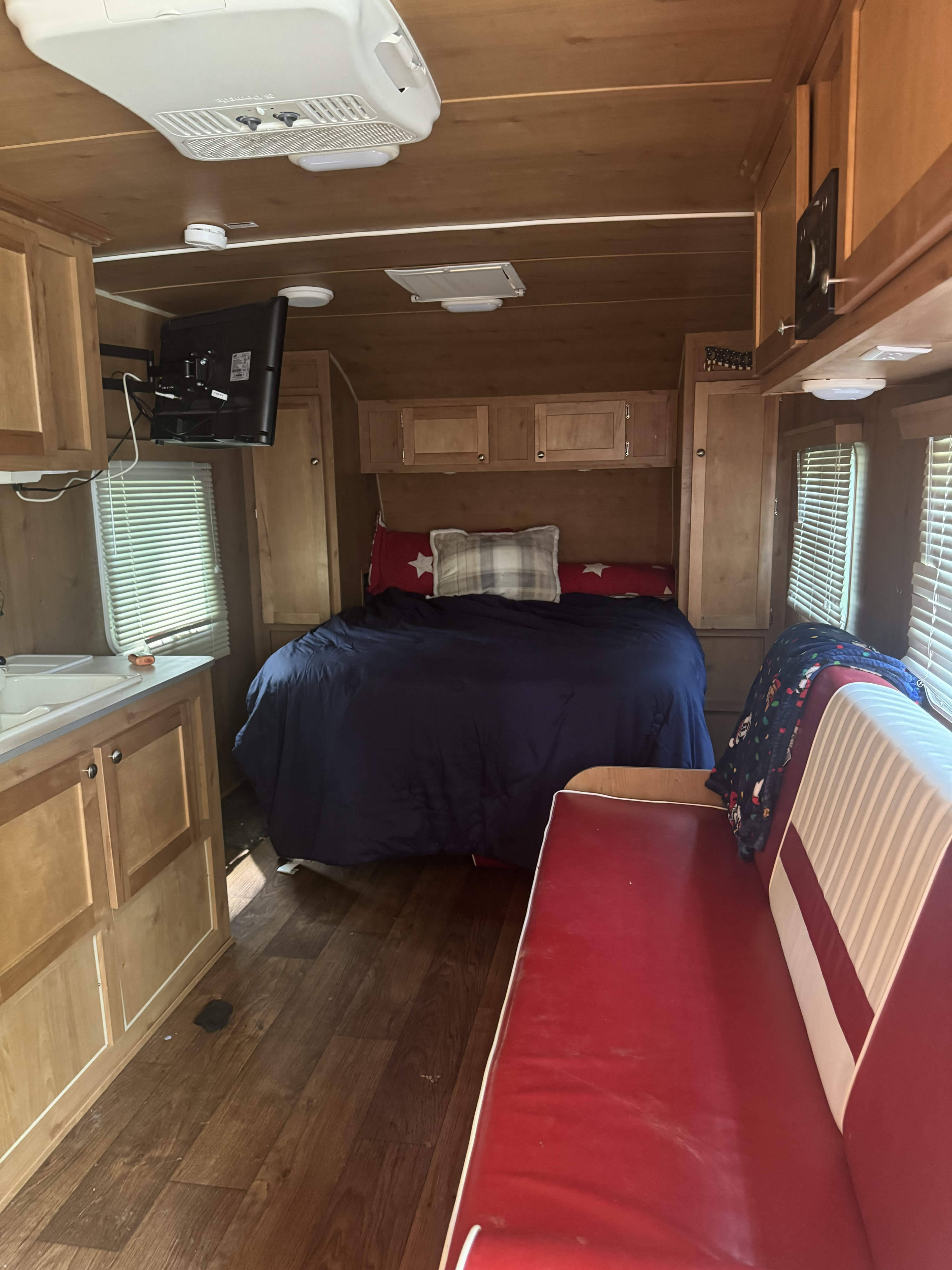 RV rental interior: A compact living space features a bed, kitchen area with sink, and a vibrant red dinette.. Riverside Travel Trailer Retro 189R 2017