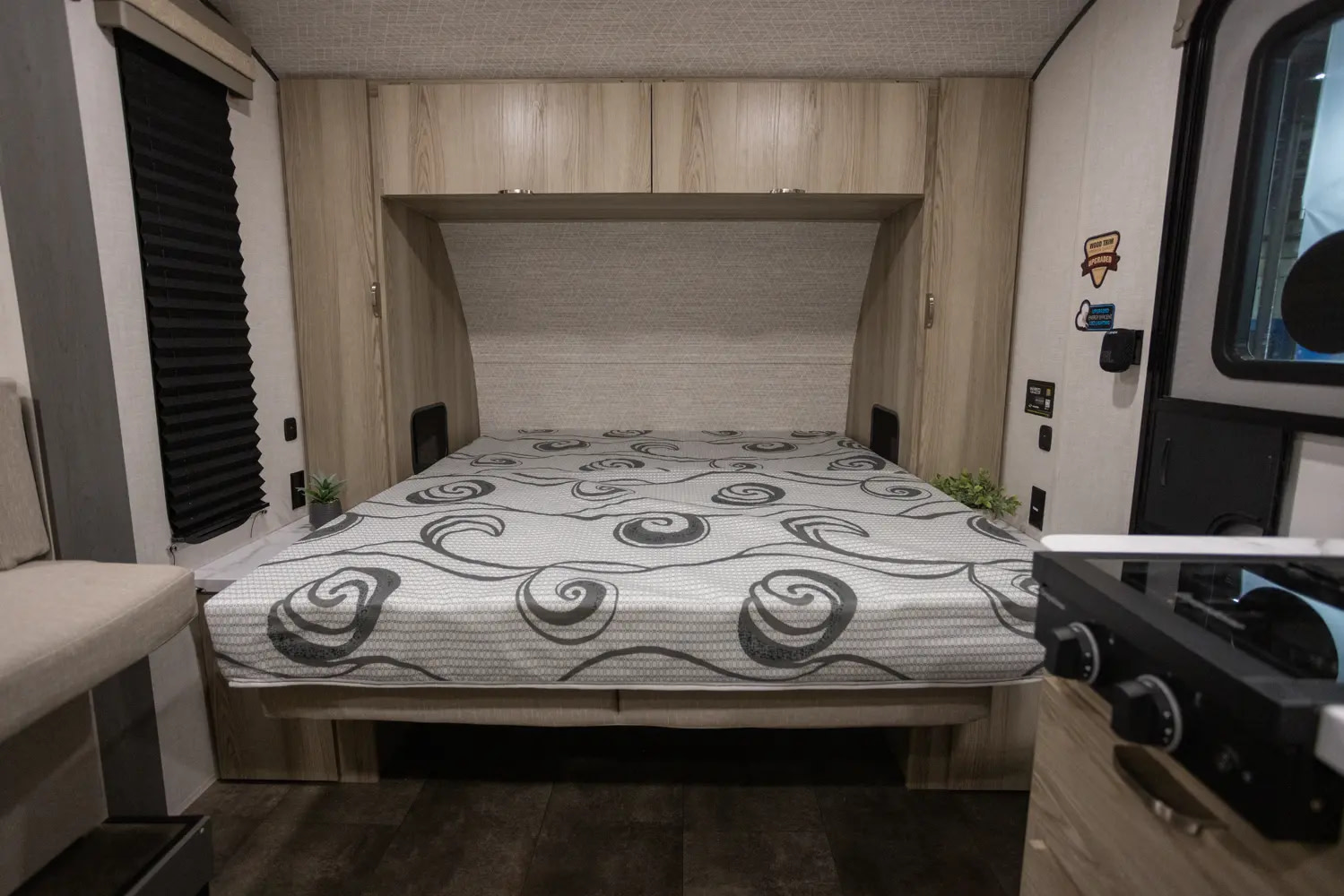 Inside an RV rental: a compact bedroom with a patterned mattress, built-in storage, and dark wood flooring.. Forest River Salem FSX 2025