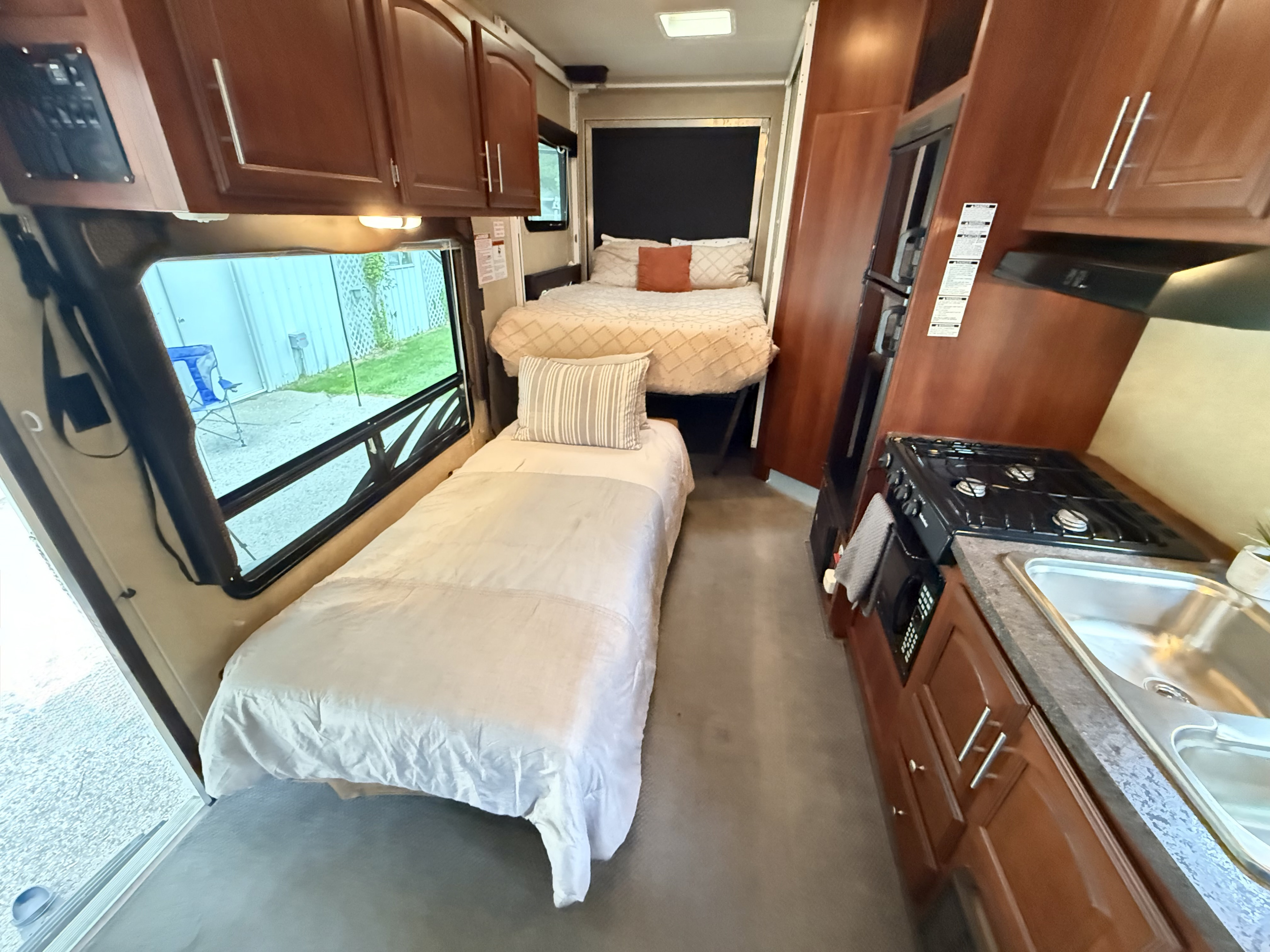 RV rental interior featuring a compact kitchen with stove & sink, a single bed, and a double bed.. Forest River Nitro Xlr 2012