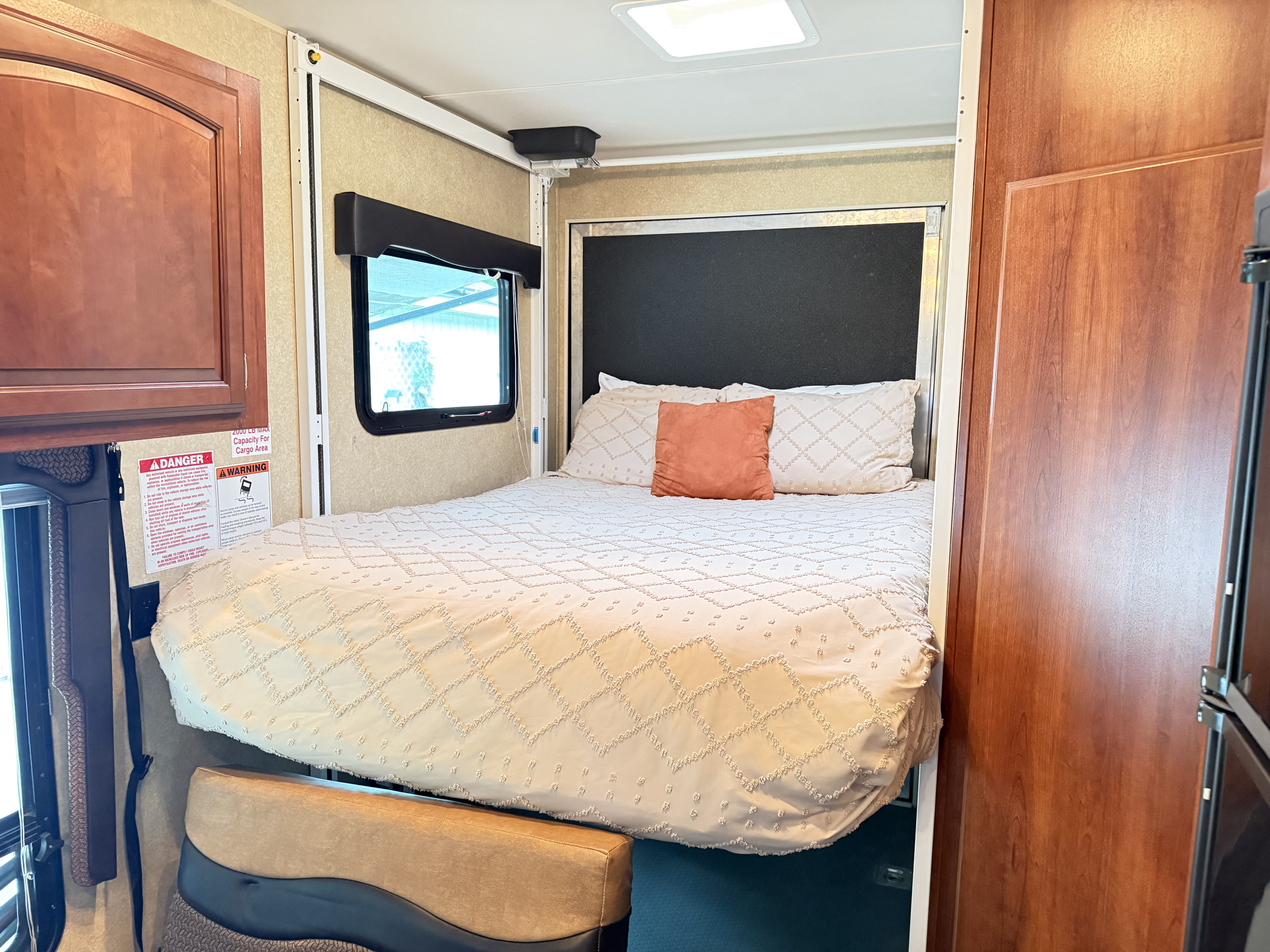 RV rental interior with a comfortable lift bed, window, and wood cabinets, suggesting a versatile cargo area.. Forest River Nitro Xlr 2012