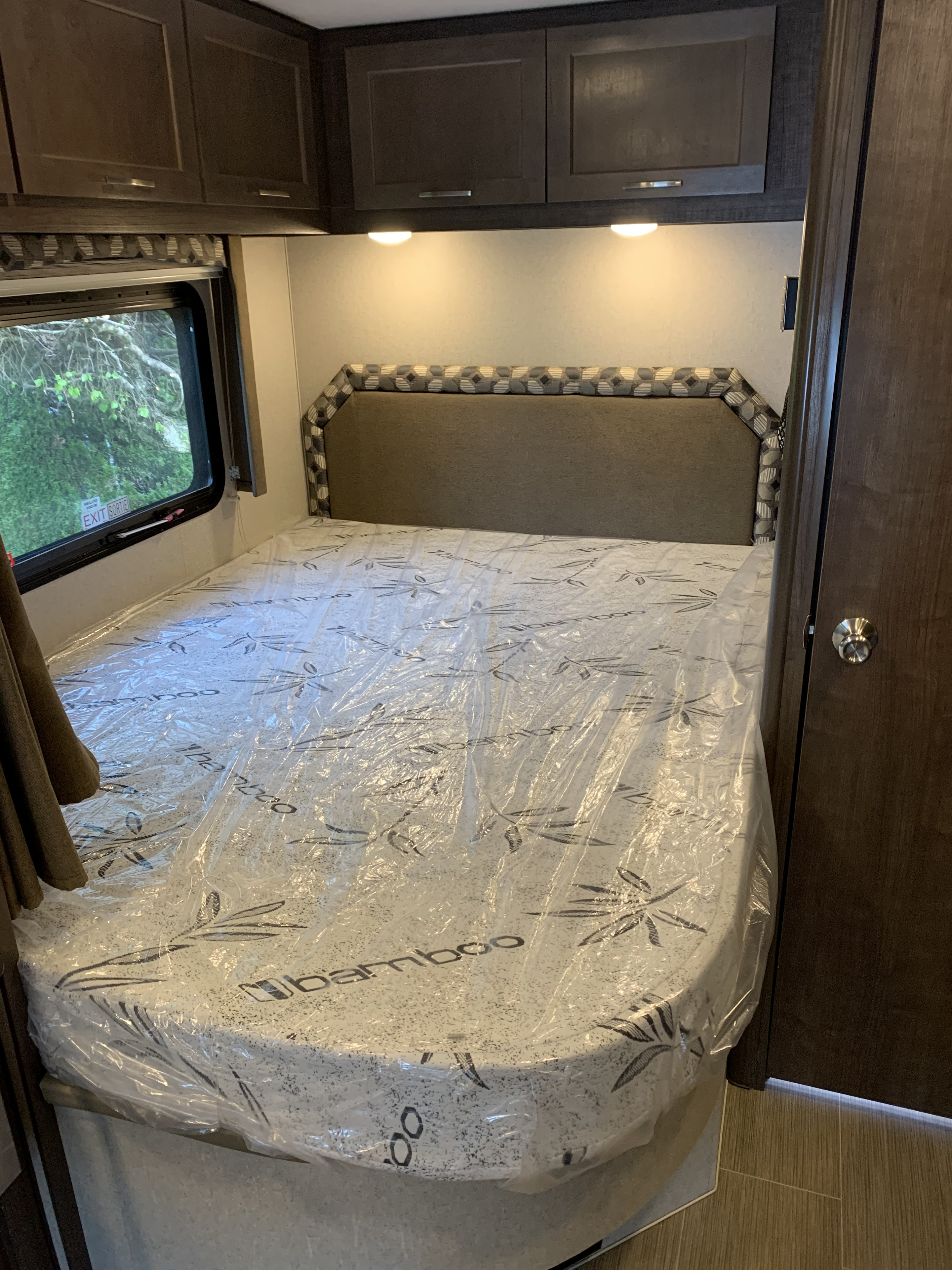 Comfortable RV rental bedroom features a new bamboo mattress in plastic, overhead cabinets, and an emergency exit window.. Adventurer Adventurer Motorhome 2019