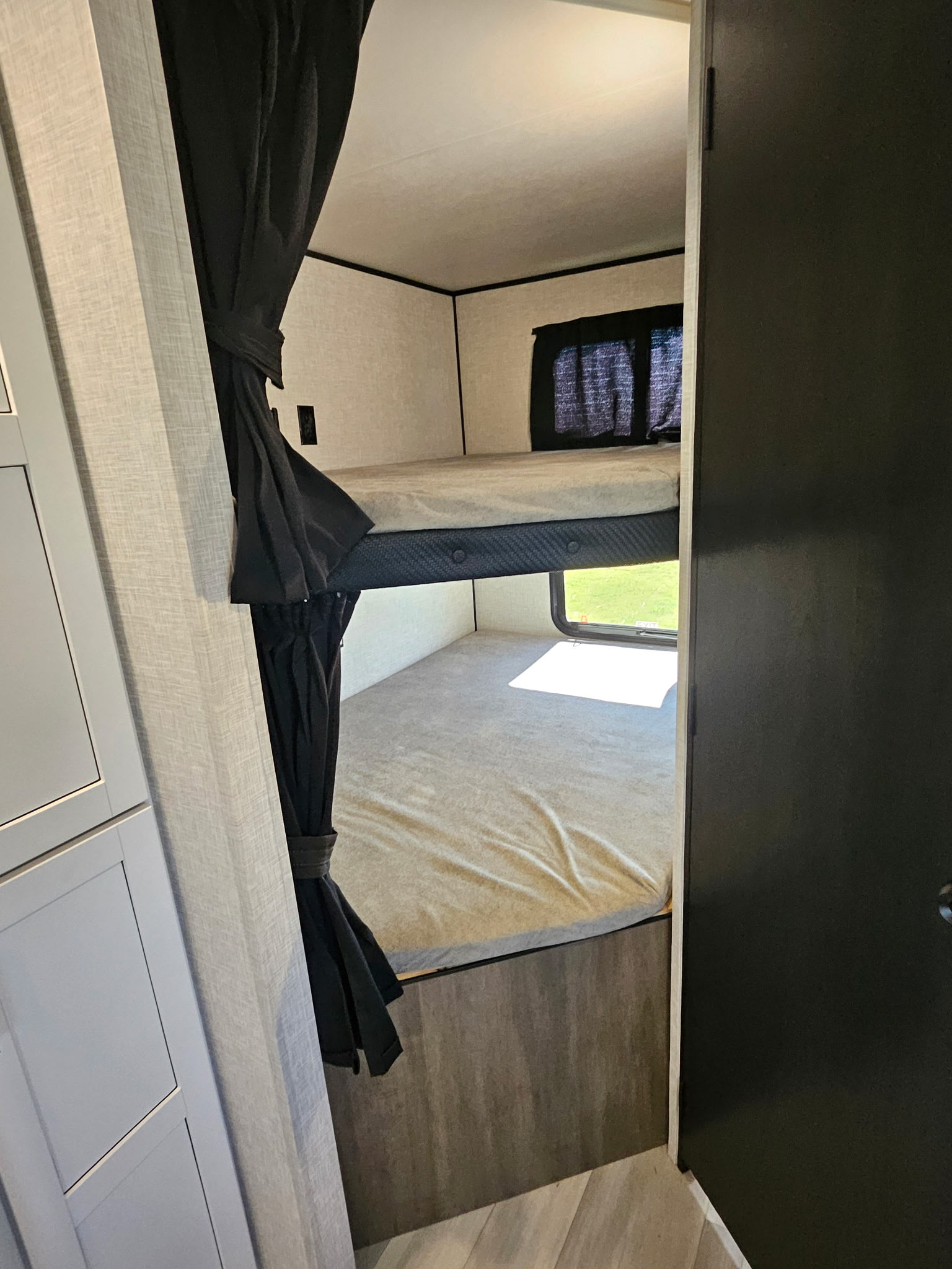 Inside an RV rental, showcasing cozy bunk beds with privacy curtains & a bright window view.. Highland Ridge Open Range 26BHS 2025