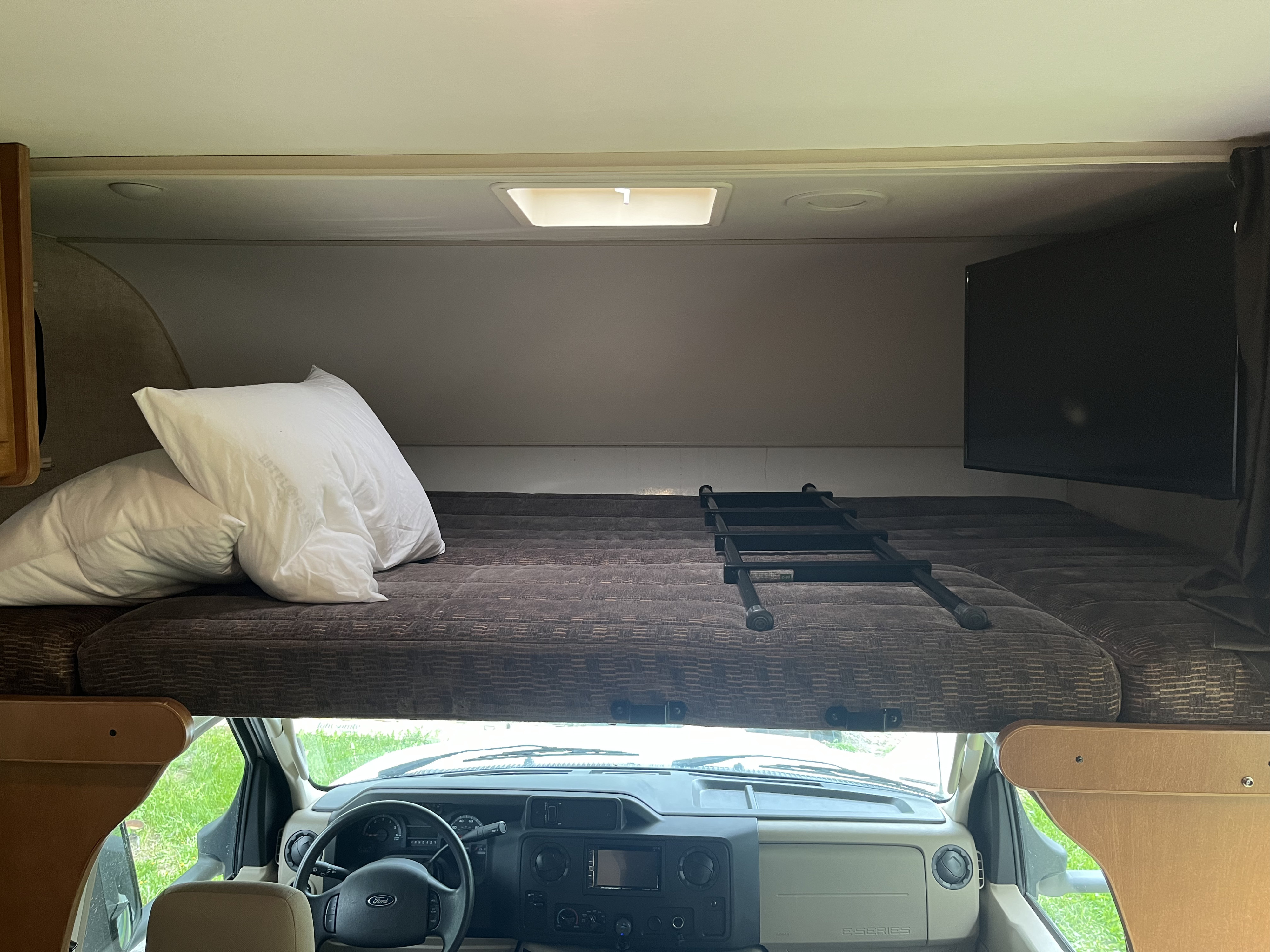 RV rental interior: spacious overhead bunk with bed, TV, & ladder, overlooking the driver's cabin.. Winnebago Minnie Winnie 2018