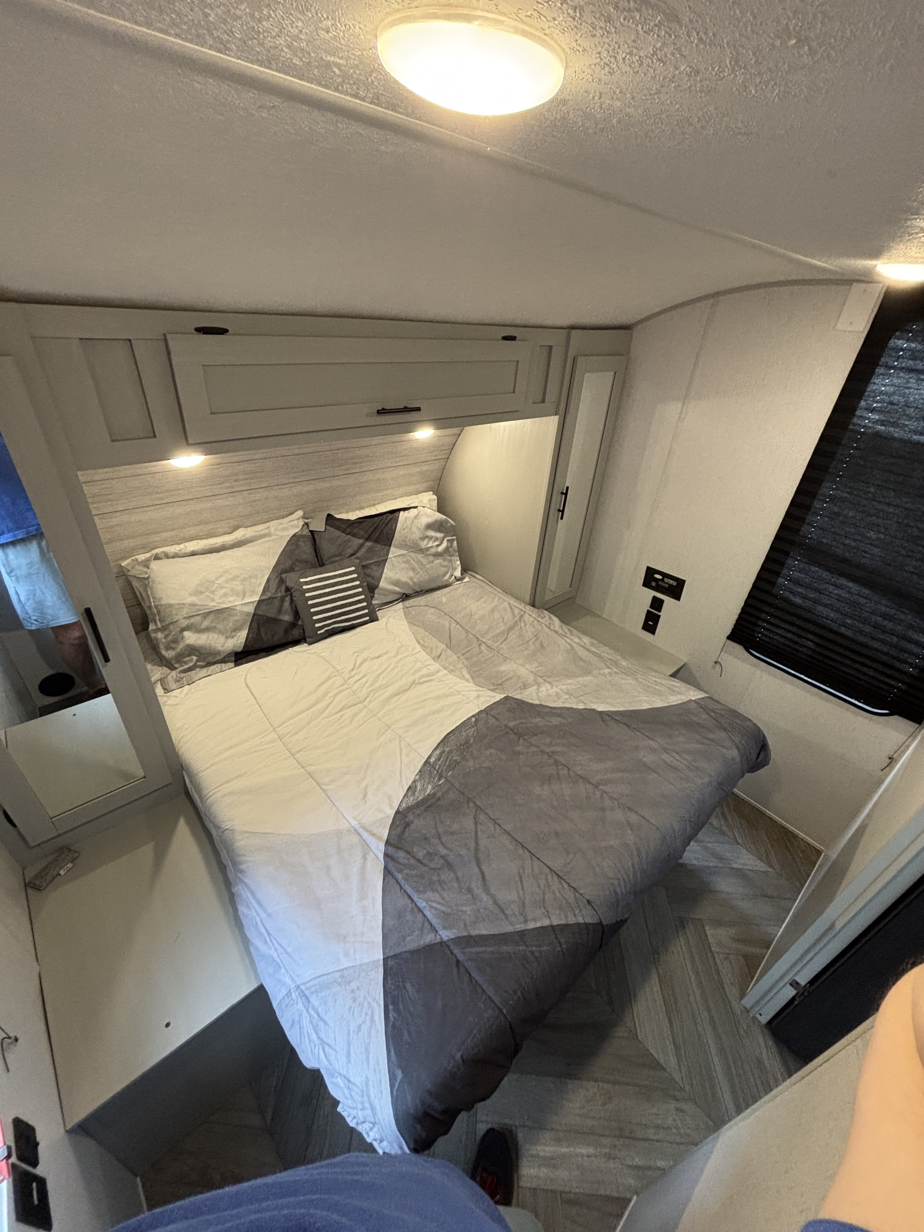 Modern RV rental bedroom with comfy bed, overhead storage, and herringbone-patterned flooring. Ideal for compact living.. Forest River Salem FSX Platinum Toy Hauler 2022