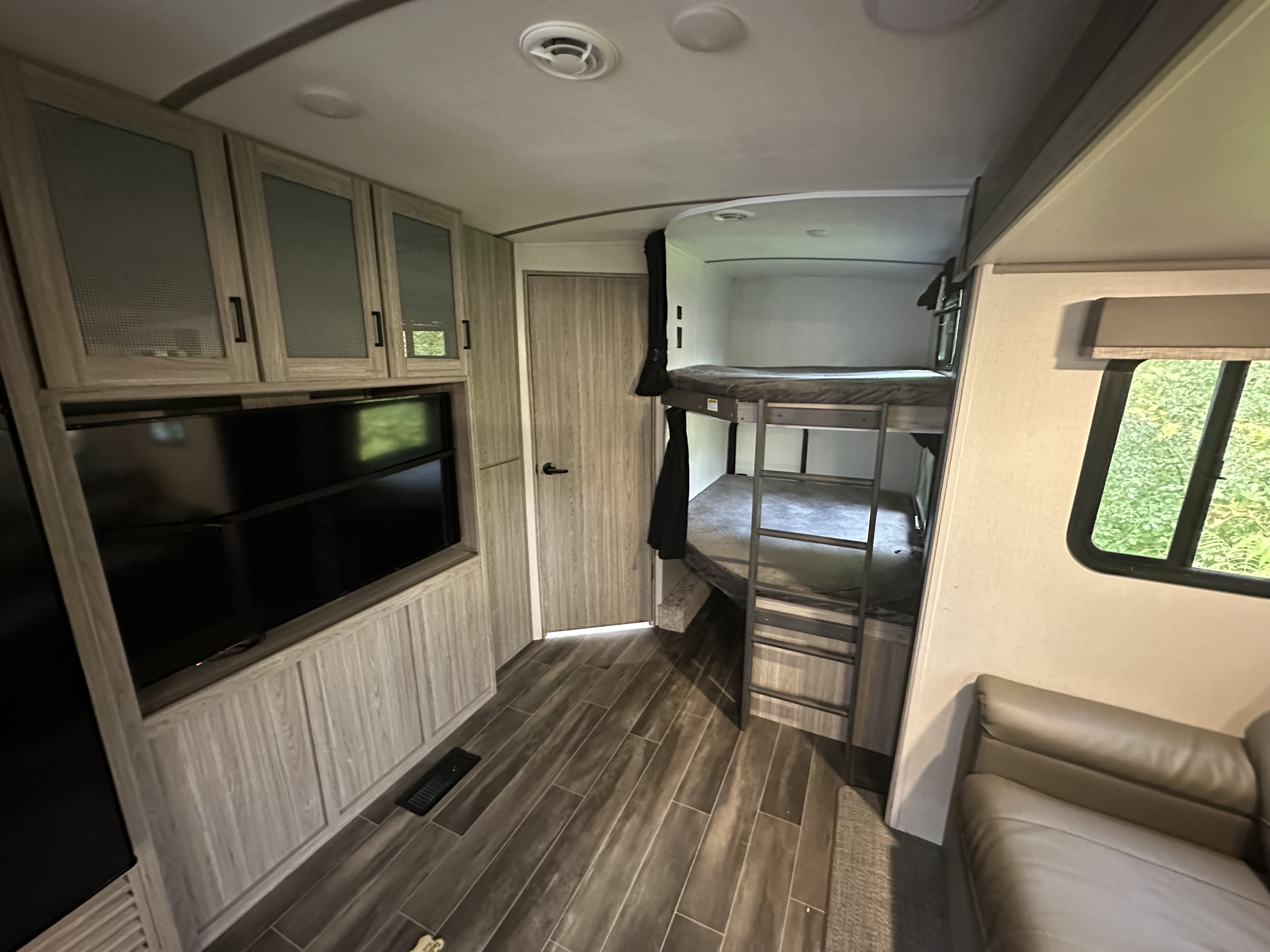 Experience this RV rental's inviting interior: bunk beds, TV, sofa, and light wood cabinetry on sleek floors.. Keystone RV Passport GT 2022