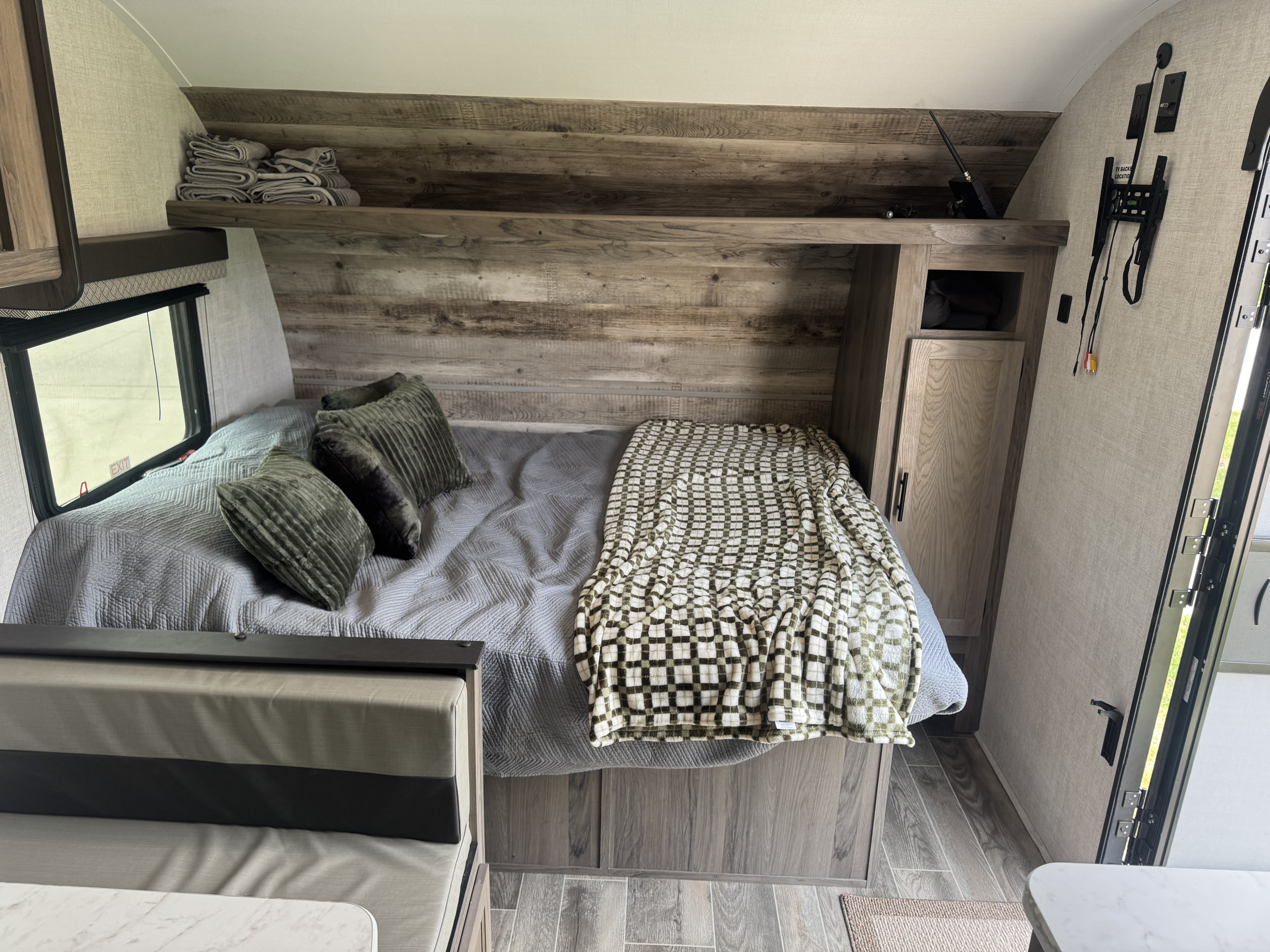 Cozy RV rental bedroom with a comfy bed, patterned blanket, wood accents, and built-in storage shelves.. Gulf Stream Ameri-Lite Super Lite 2022