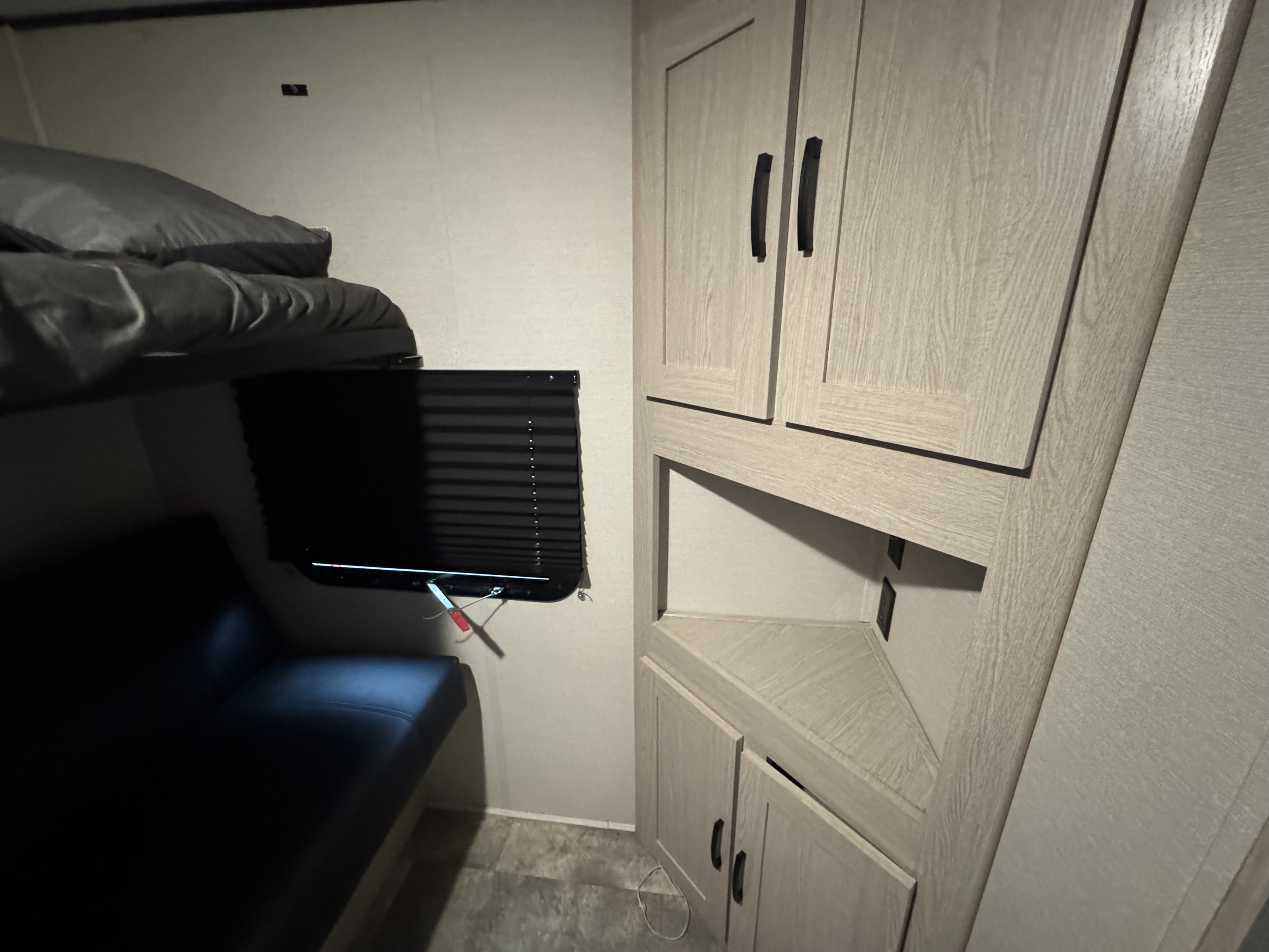 RV rental interior featuring bunk beds, a wall-mounted TV, and light-colored corner storage cabinets.. Coachmen Apex 2022