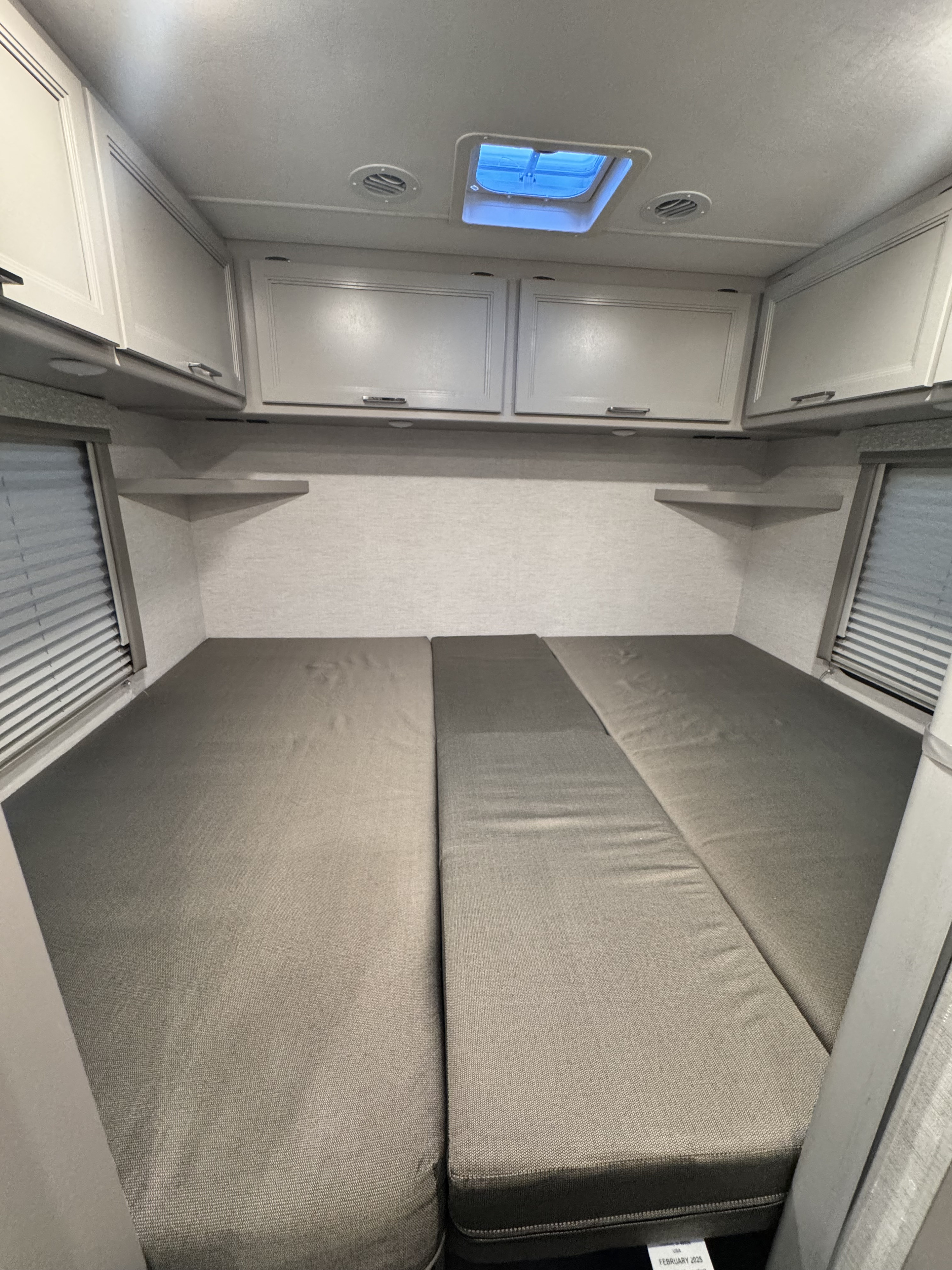 Well-arranged rv rental interior: two sleeping areas with overhead cabinets, corner shelves, and ceiling vents/skylight.. Thor Motorcoach Four Winds 2025