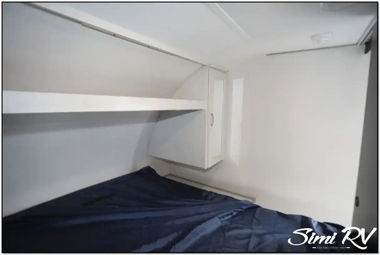 RV rental: Sleeping area with dark blue bed, overhead shelf, and storage cabinet.. Primetime RV Tracer 2022
