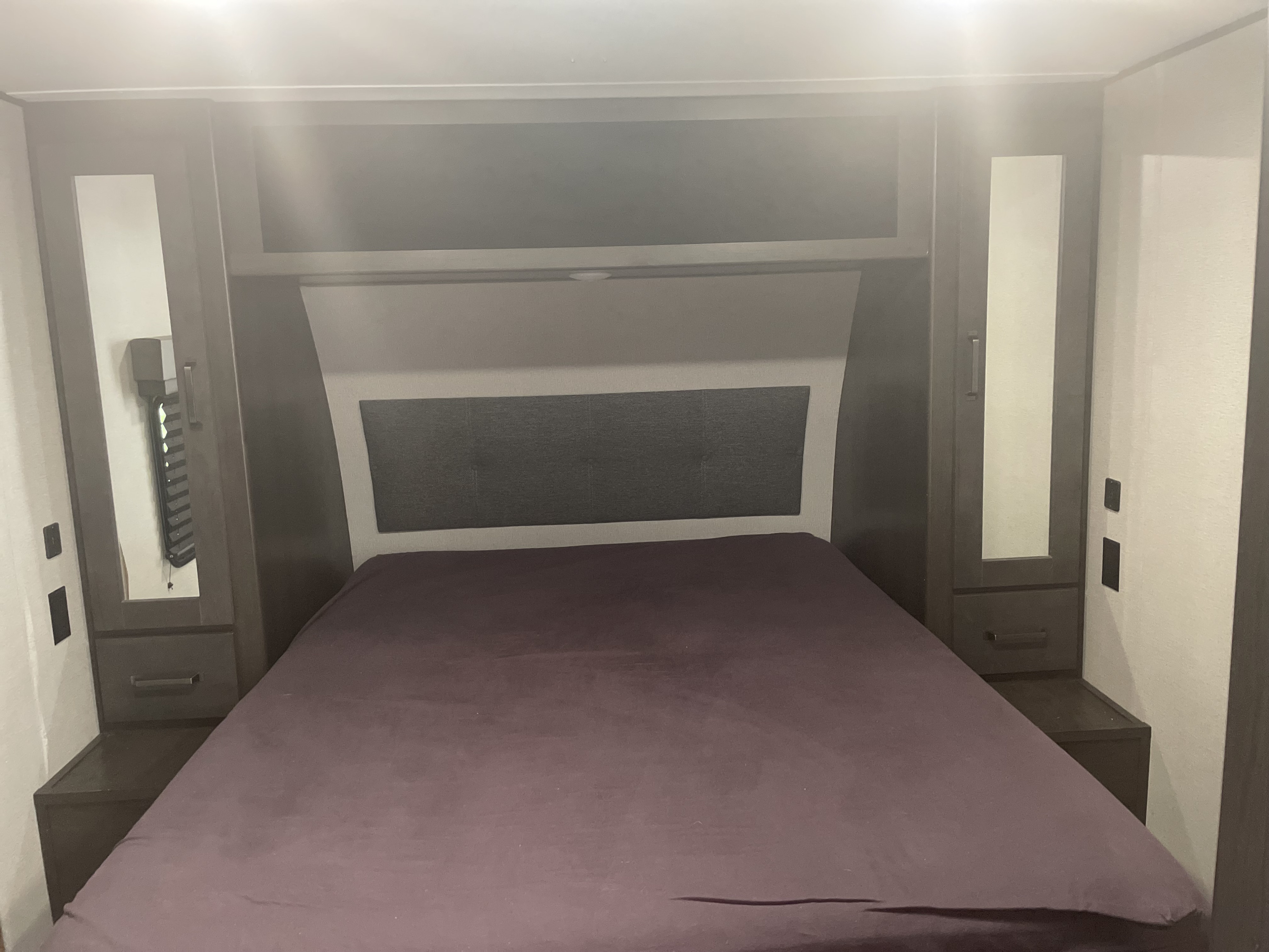 Cozy RV rental bedroom with built-in storage, a comfortable bed, and convenient nightstands for travel.. Grand Design Transcend 2023