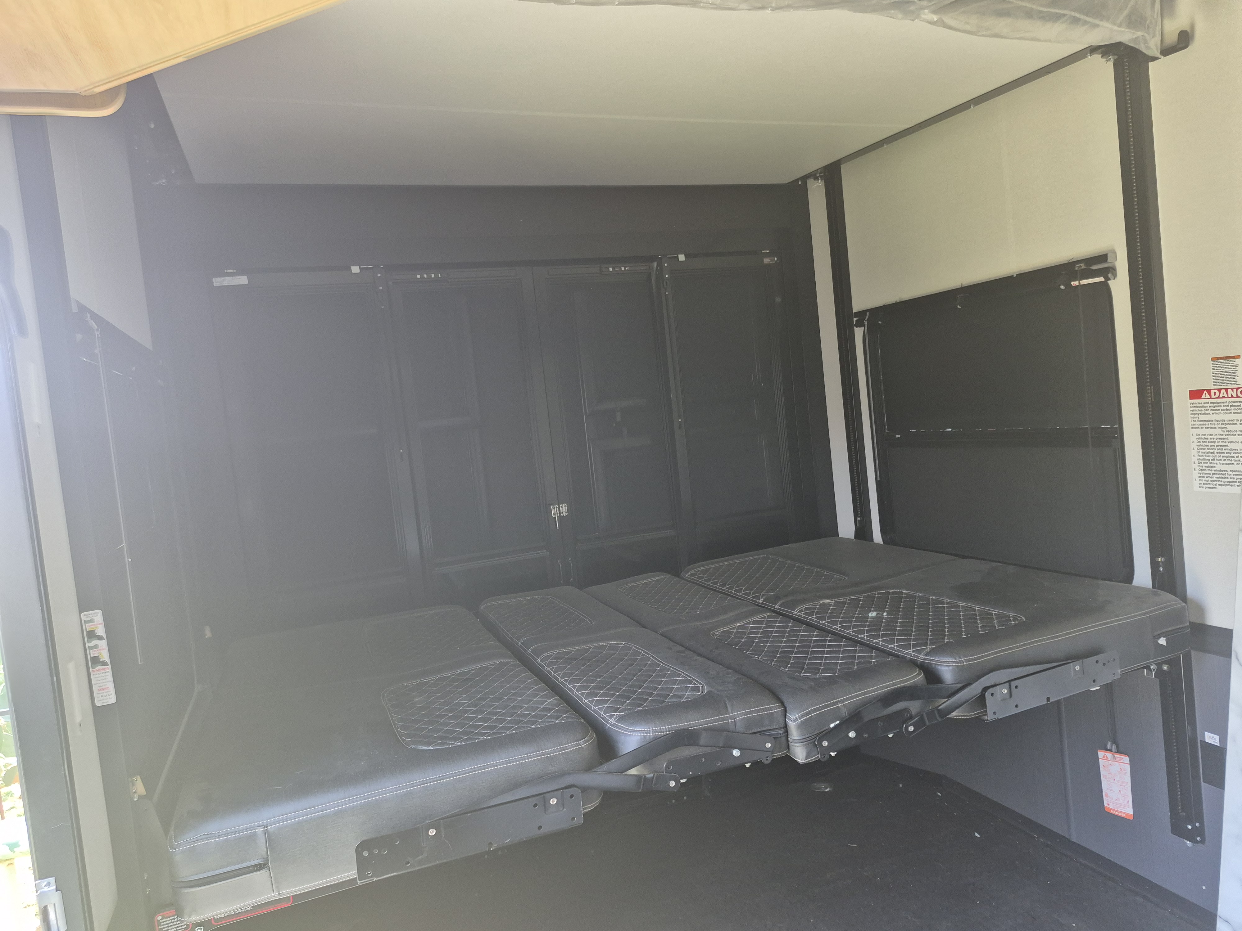This RV rental's toy hauler interior features a pull-down bed, converting from cargo to comfortable sleeping space.. Heartland RVs Cyclone Toy Hauler 2024