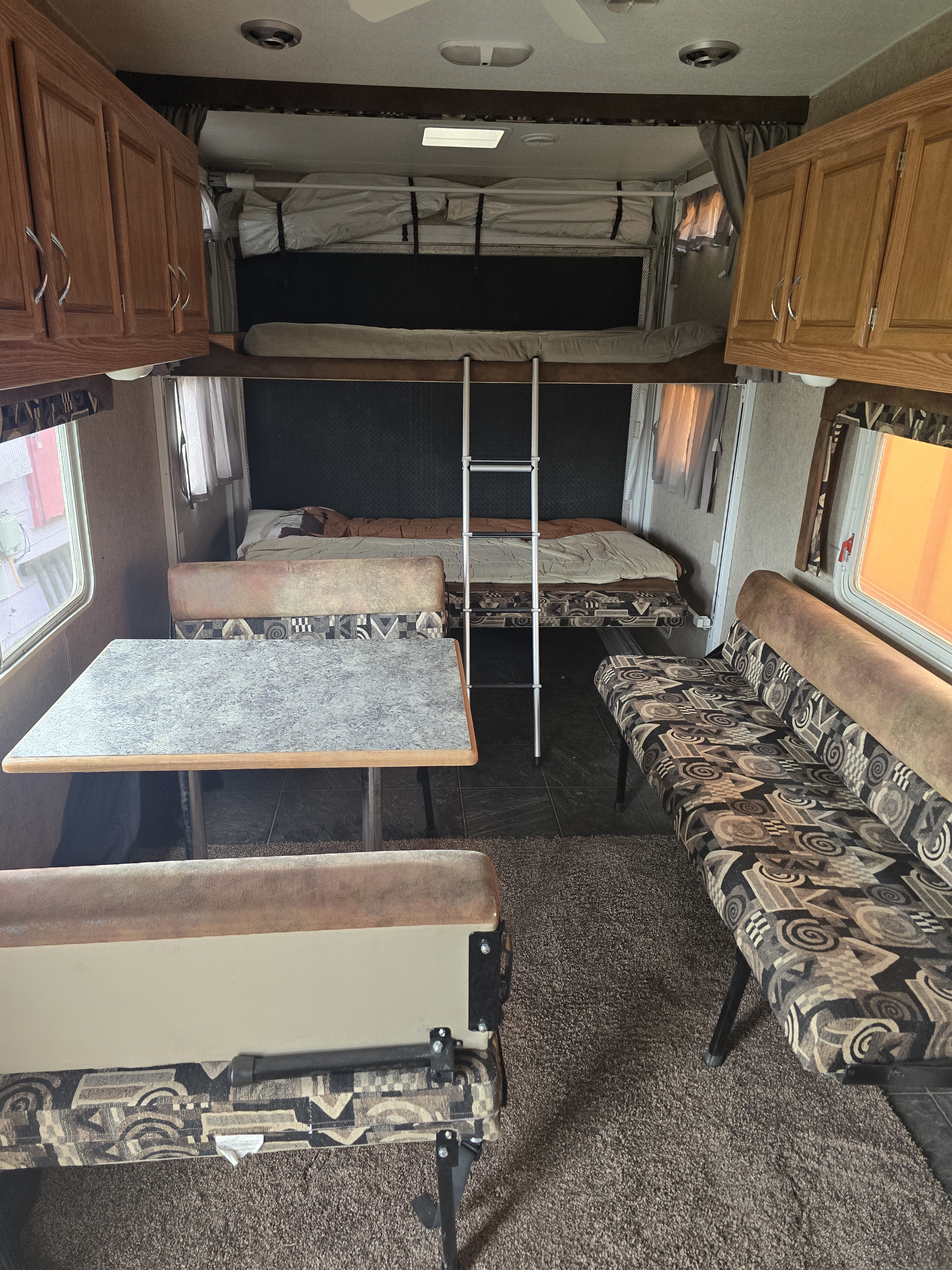 RV rental interior: dinette with table, lower bed, upper bunk with ladder, and patterned seating. Ready for your adventure.. Eclipse Recreational Vehicles Attitude 2008