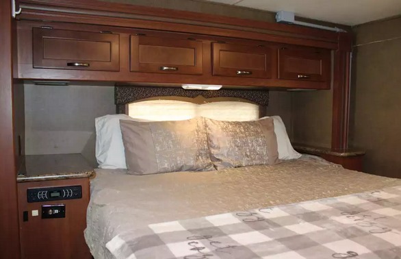 RV rental: Plush master bedroom with overhead storage, built-in nightstands, and media controls.. Thor Four Winds 2015