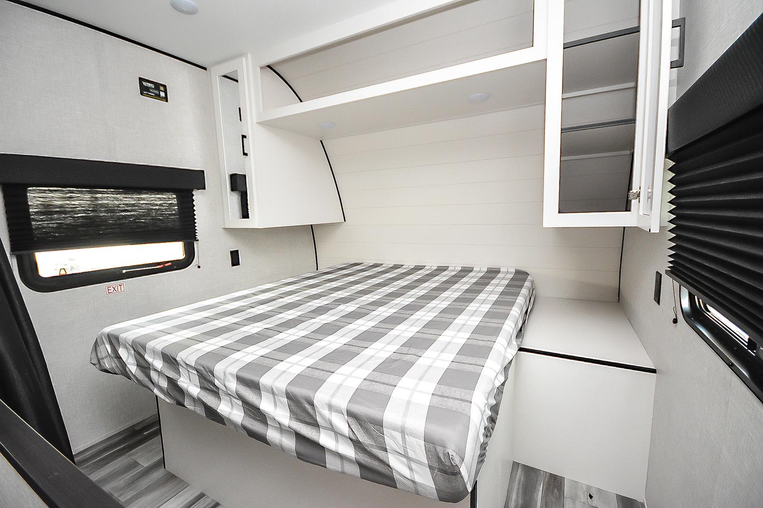 Cozy RV rental bedroom featuring a grey plaid bed, overhead storage, and a window with blinds.. Jayco Jay Flight 260BH 2025