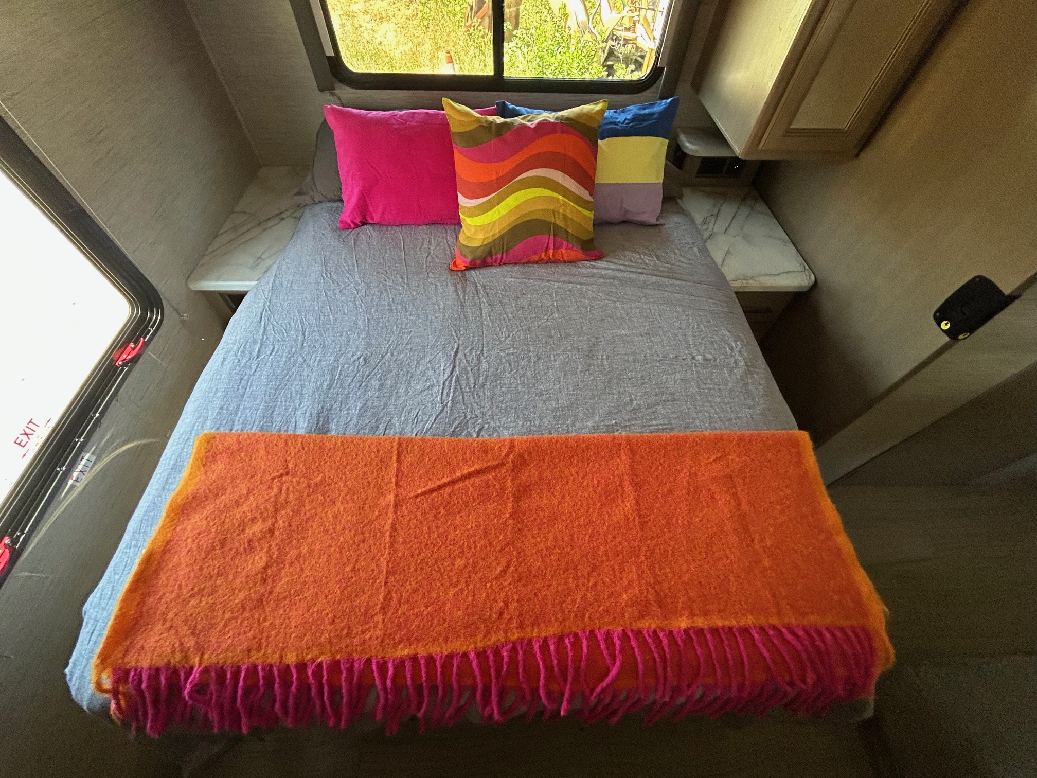 Cozy RV rental bedroom with vibrant pillows and blanket. Perfect for travel adventures!. Thor Coleman 2022