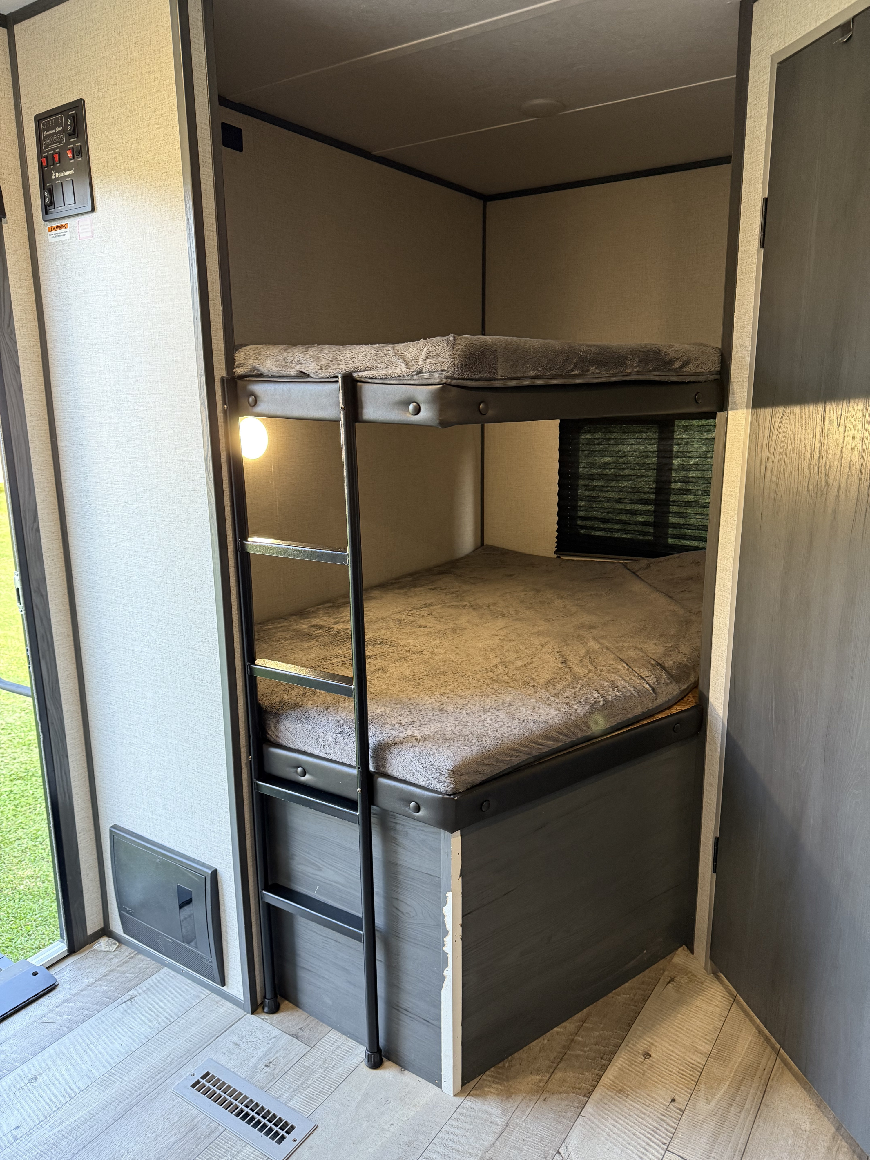 Cozy bunk beds in an RV rental, featuring a control panel, light, and window for comfortable travel and sleeping.. Aspen Trail Aspen Trail Trailer 2022