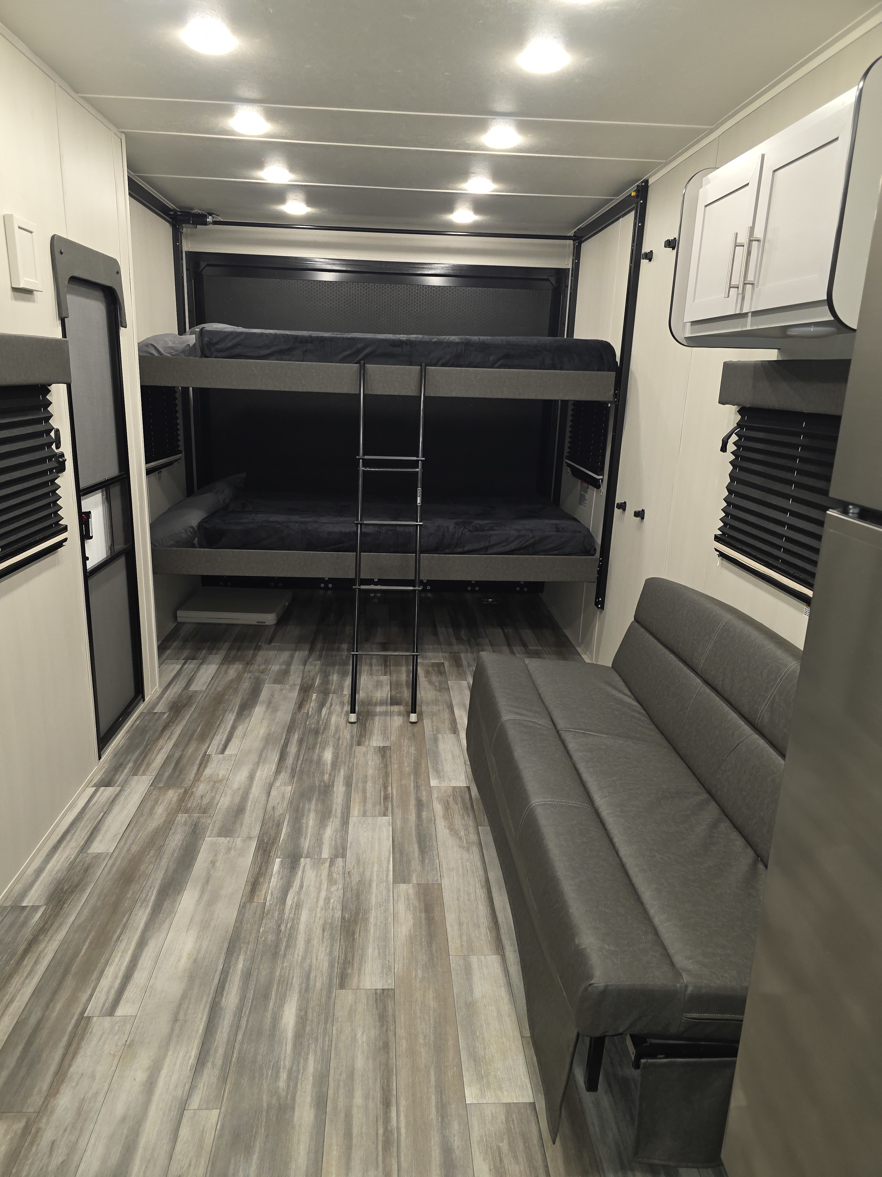 Clean rv rental interior showcasing bunk beds, grey sofa, and sleek wood-look flooring.. Dune Sport Dynamite 2025