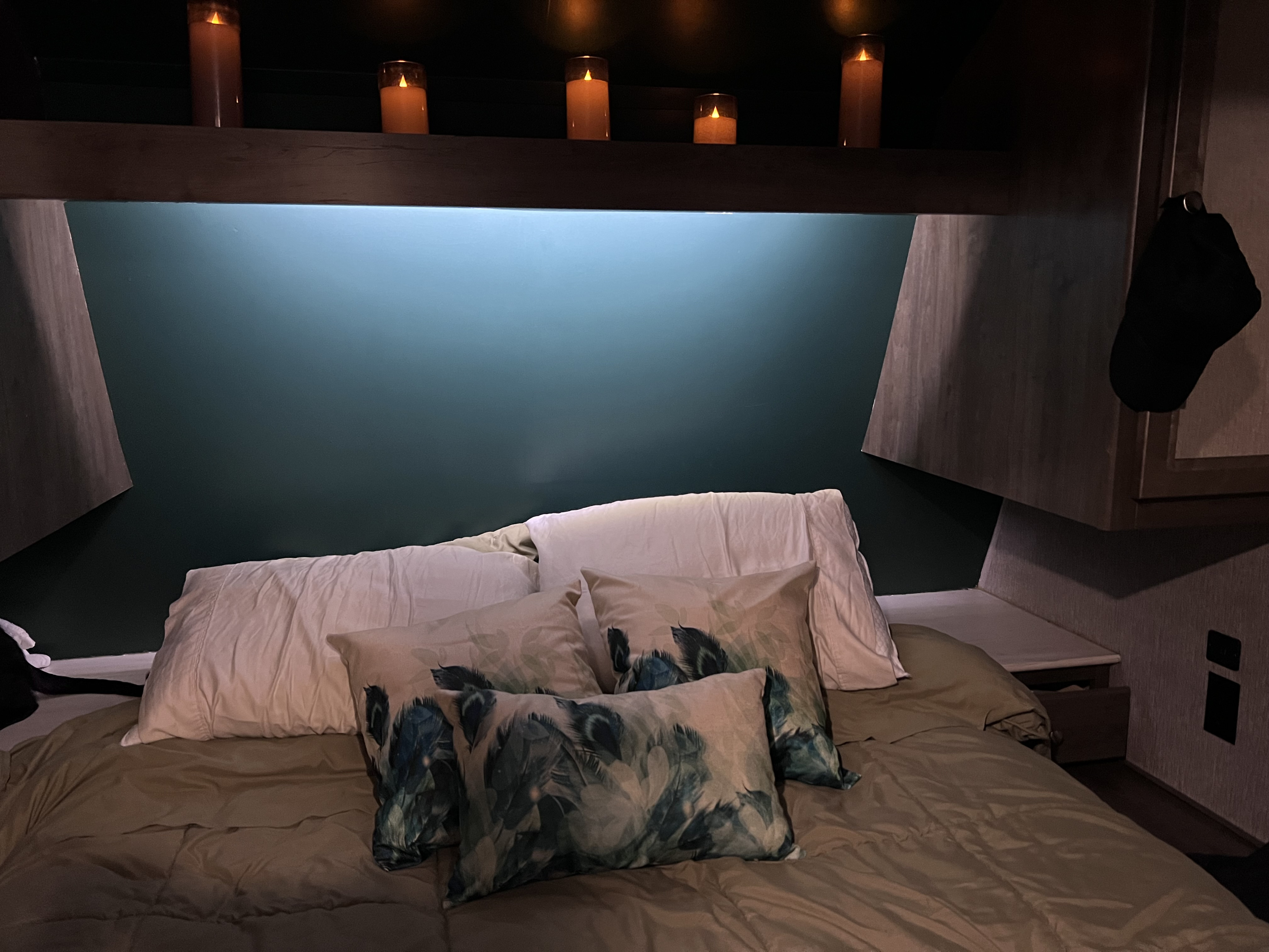 Cozy RV rental bedroom features a teal accent wall, ambient LED candles, and comfy feather pillows.. Coleman Lantern Toy Hauler Series M-250TQ- Pet Friendly + 6 person tent 2020