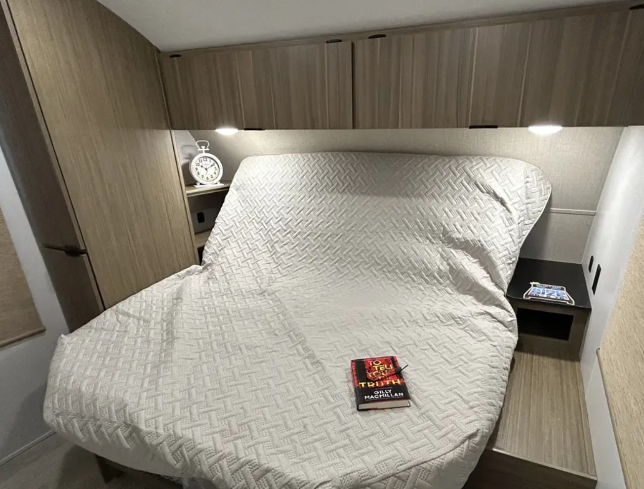 RV rental bedroom: Cozy quilted bed, built-in shelving with alarm clock & book, plus overhead lights.. Forest River Salem 2025