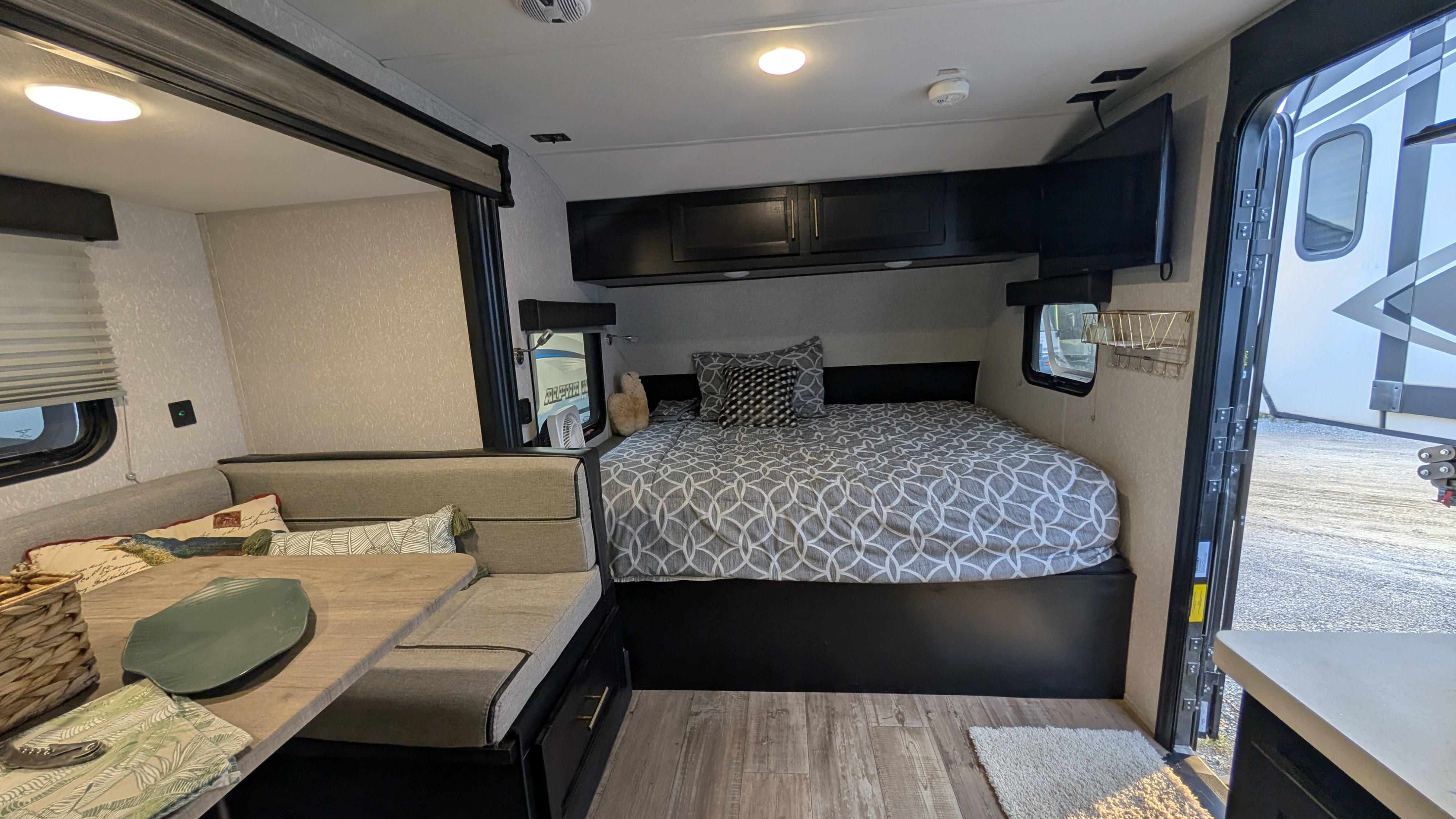 This RV rental interior features a cozy bed, dinette seating, and modern amenities for comfortable travel.. Forest River Cherokee Wolf Pup Black Label 2022