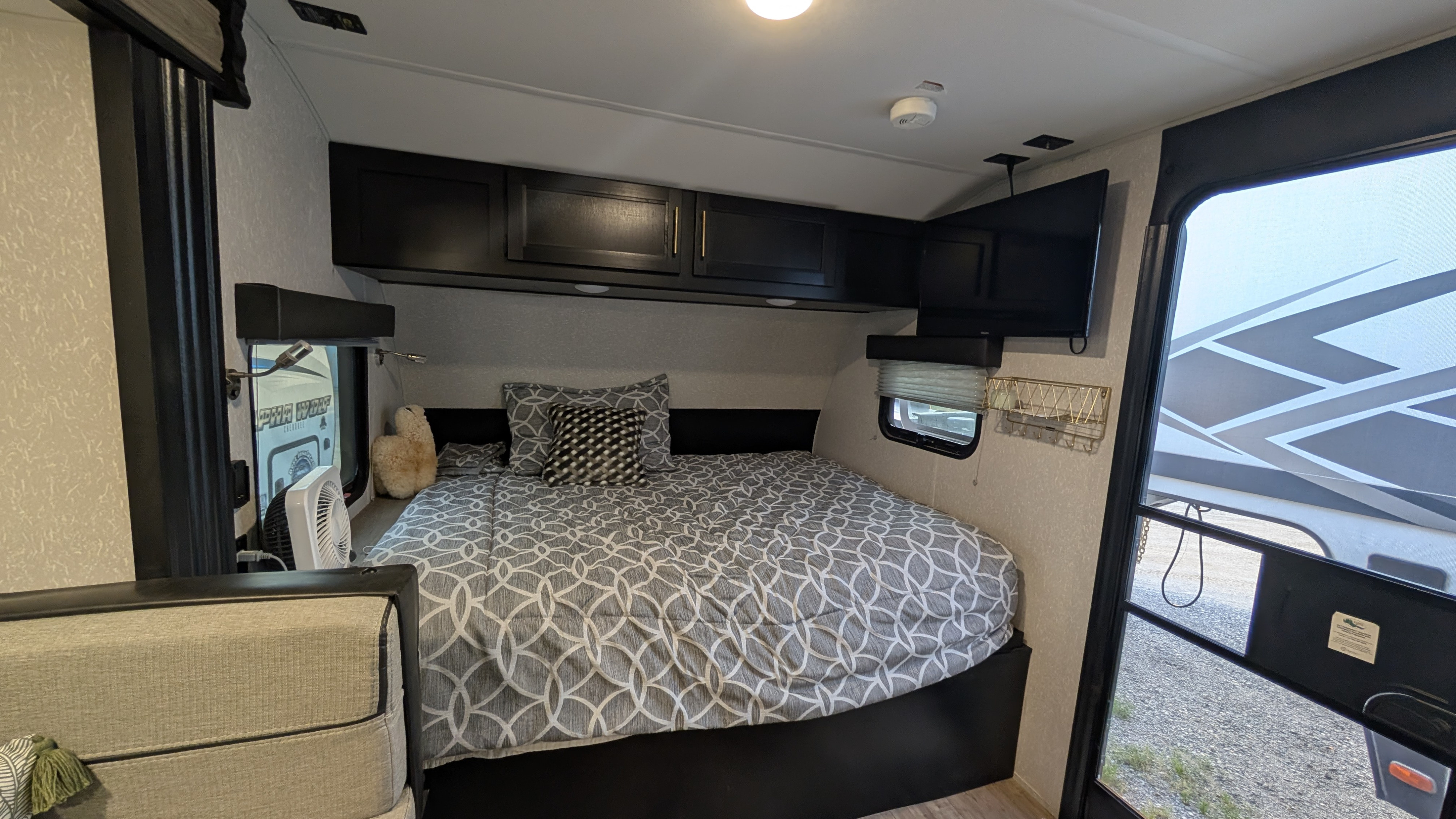 Cozy RV rental bedroom with overhead cabinets, a comfortable bed, and TV, perfect for travel.. Forest River Cherokee Wolf Pup Black Label 2022