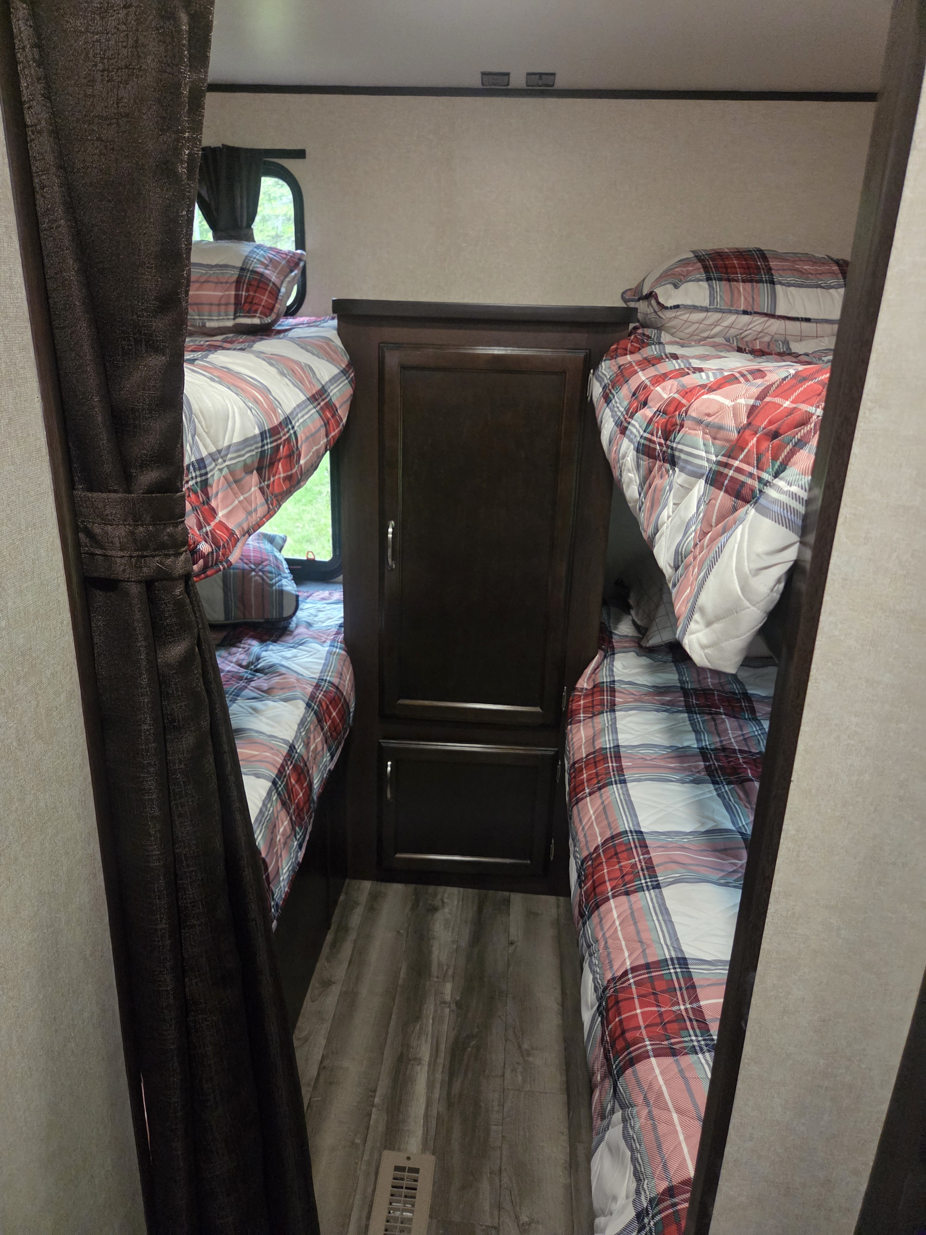 Cozy RV rental bunk beds with plaid bedding and central storage.. Jayco Jay Flight SLX 2018