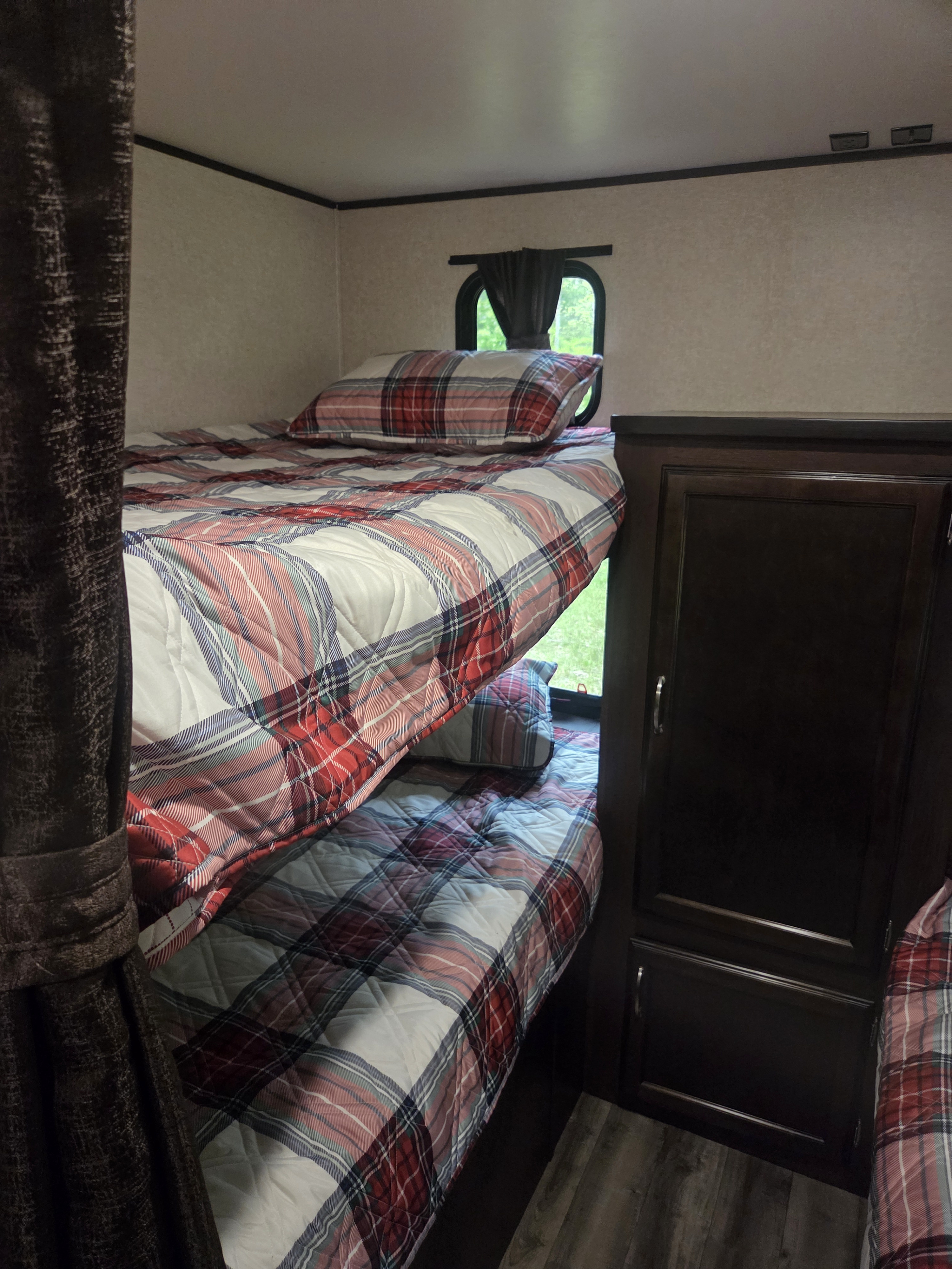 Cozy RV rental bunk beds feature red & blue plaid bedding and dark wood cabinets, perfect for family adventures.. Jayco Jay Flight SLX 2018