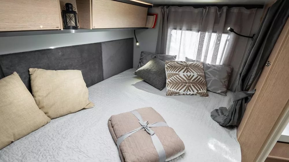 Cozy rv rental bedroom featuring a comfortable bed, soft pillows, overhead storage, and reading lights for a relaxing trip.. Giottiline C60 2025