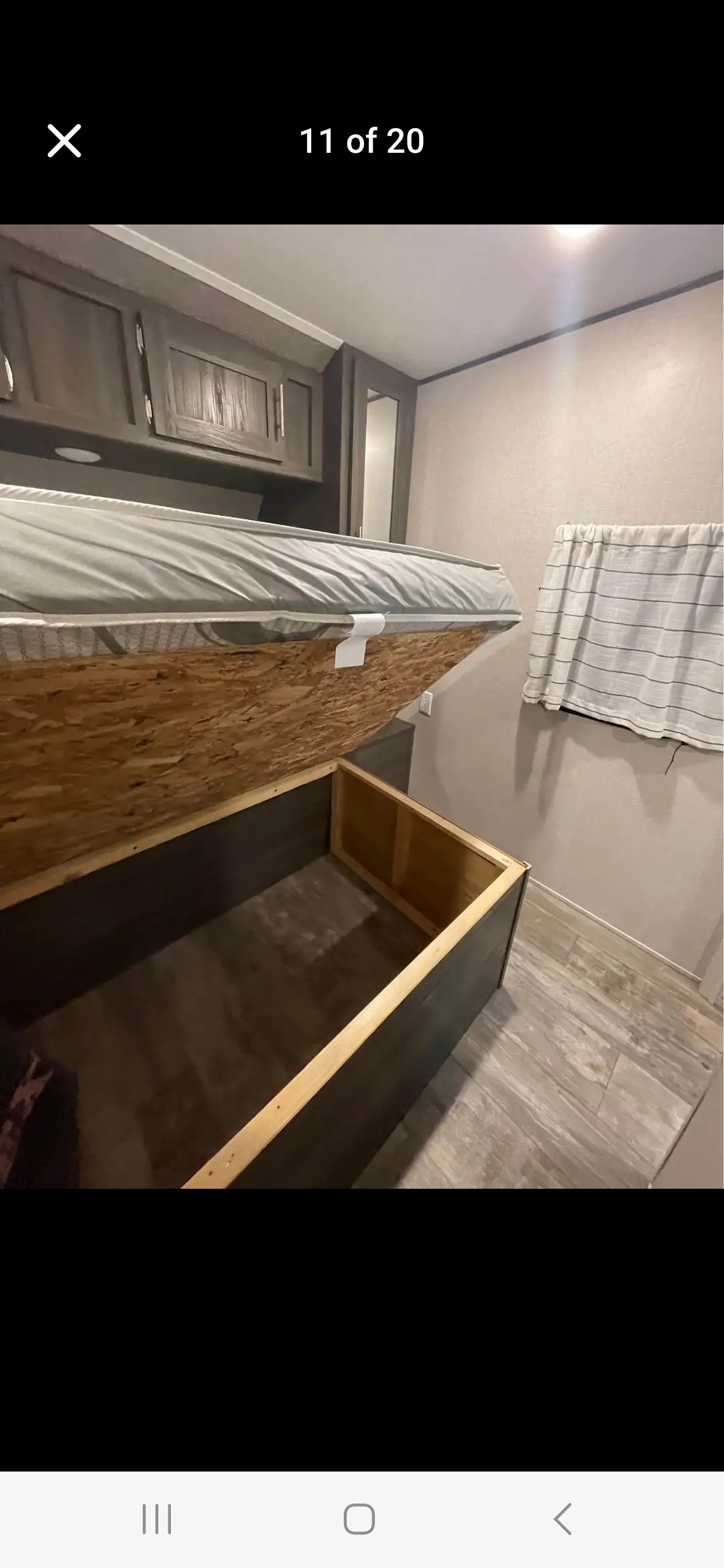 RV rental bedroom: bed lifted to show spacious under-bed storage, with overhead cabinets & wood-look floor.. forester shasta 2021