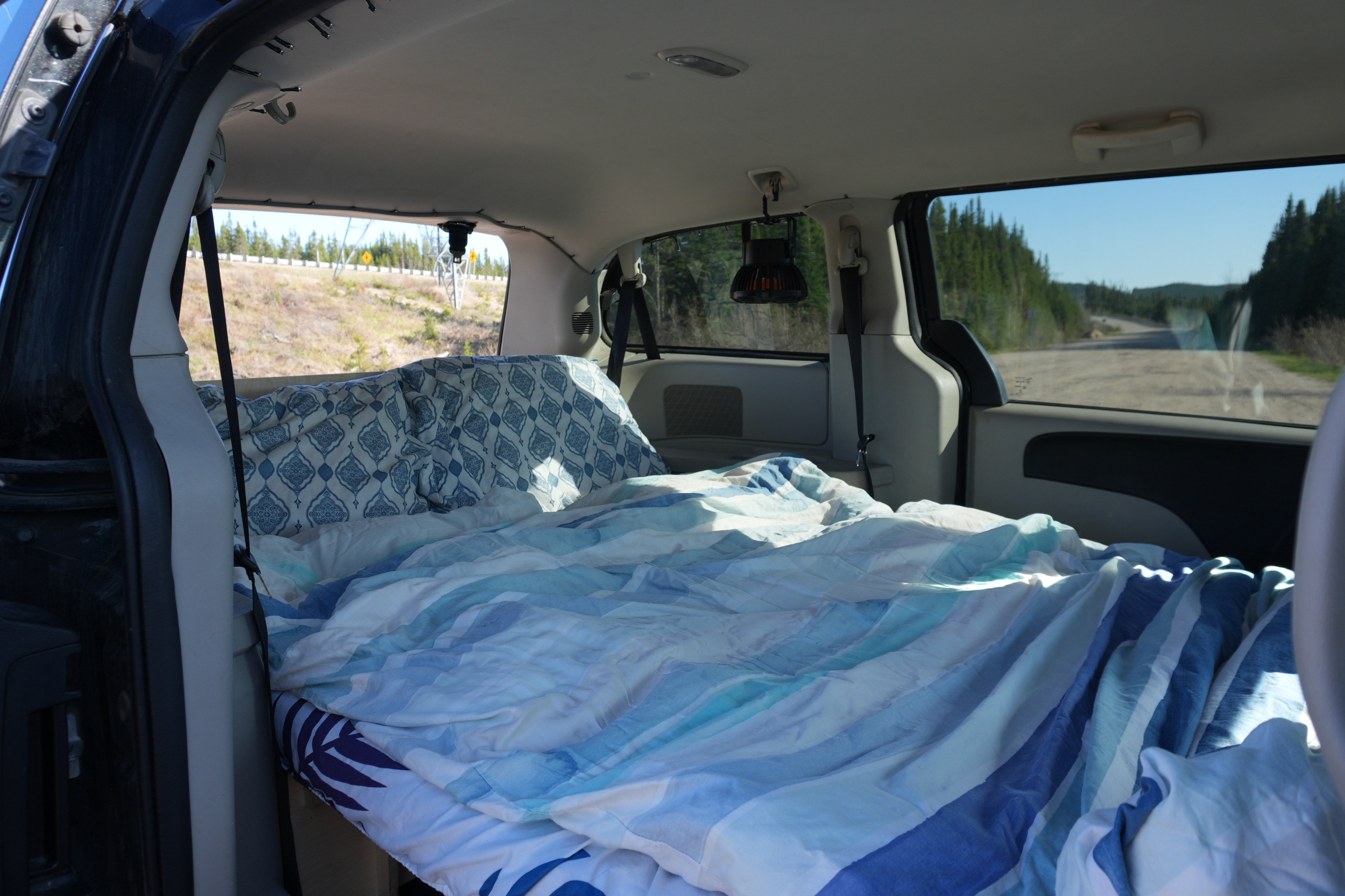 Interior of an RV rental: a comfy bed setup in a minivan, perfect for car camping and road trip adventures.. Dodge Grand Caravan 2013