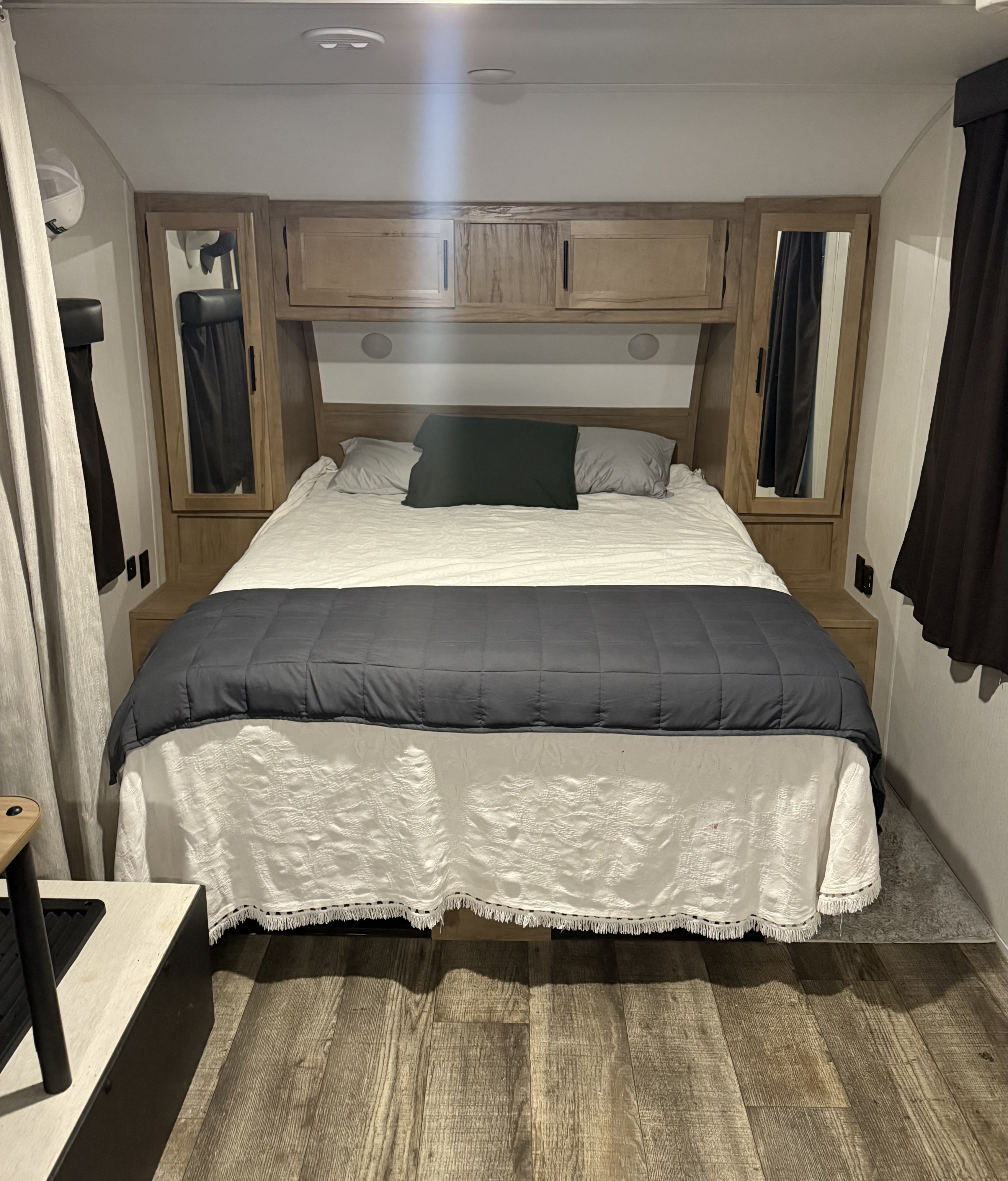 Cozy RV rental bedroom featuring a comfortable bed, built-in wooden cabinets, and mirrored storage on both sides.. Forest River Cherokee Grey Wolf Black Label 2023