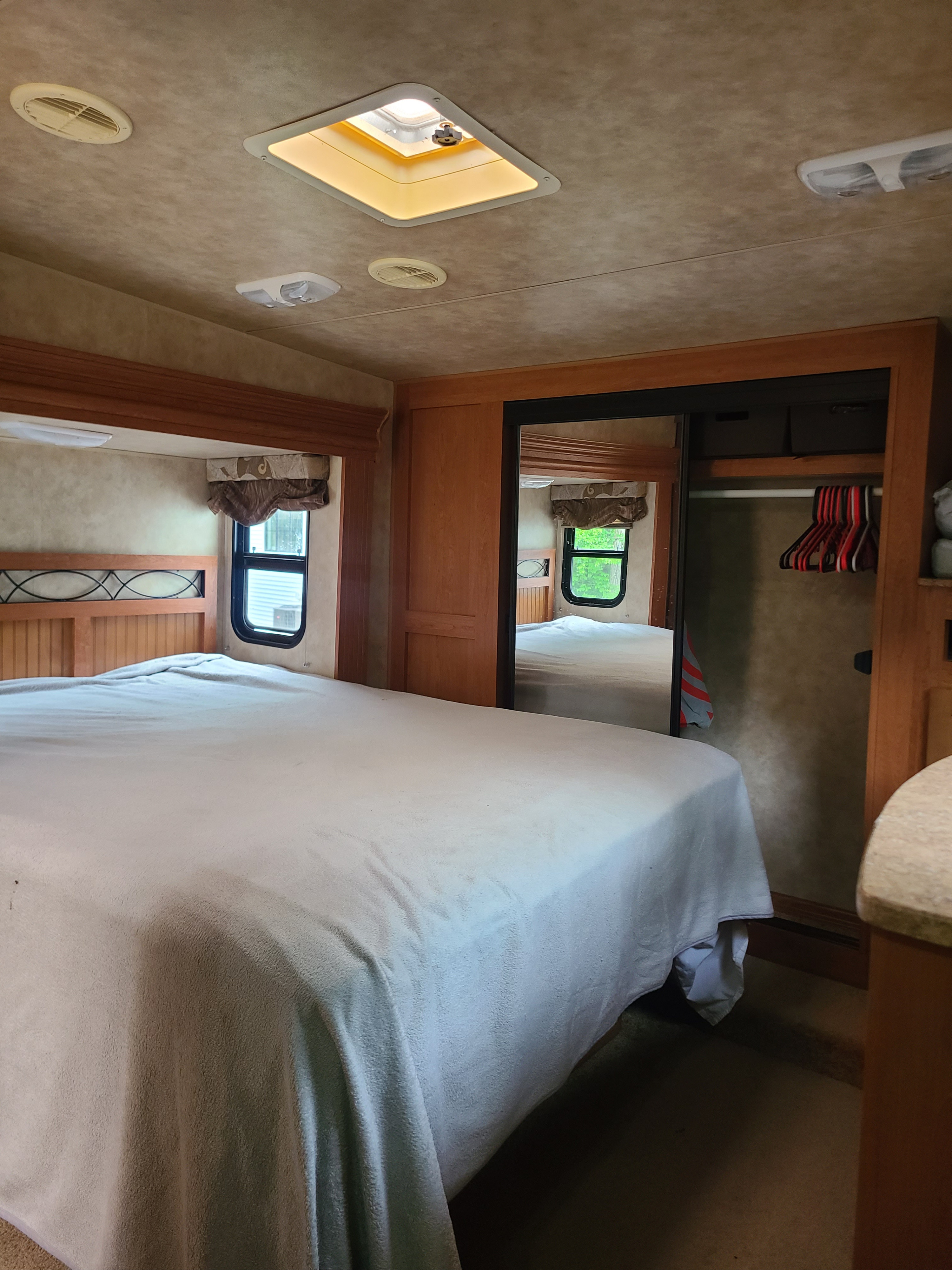 RV rental bedroom showcasing a large bed, wood finishes, mirrored closet, and windows. A cozy interior for your next adventure.. Durango Durango Fifth Wheel 2009